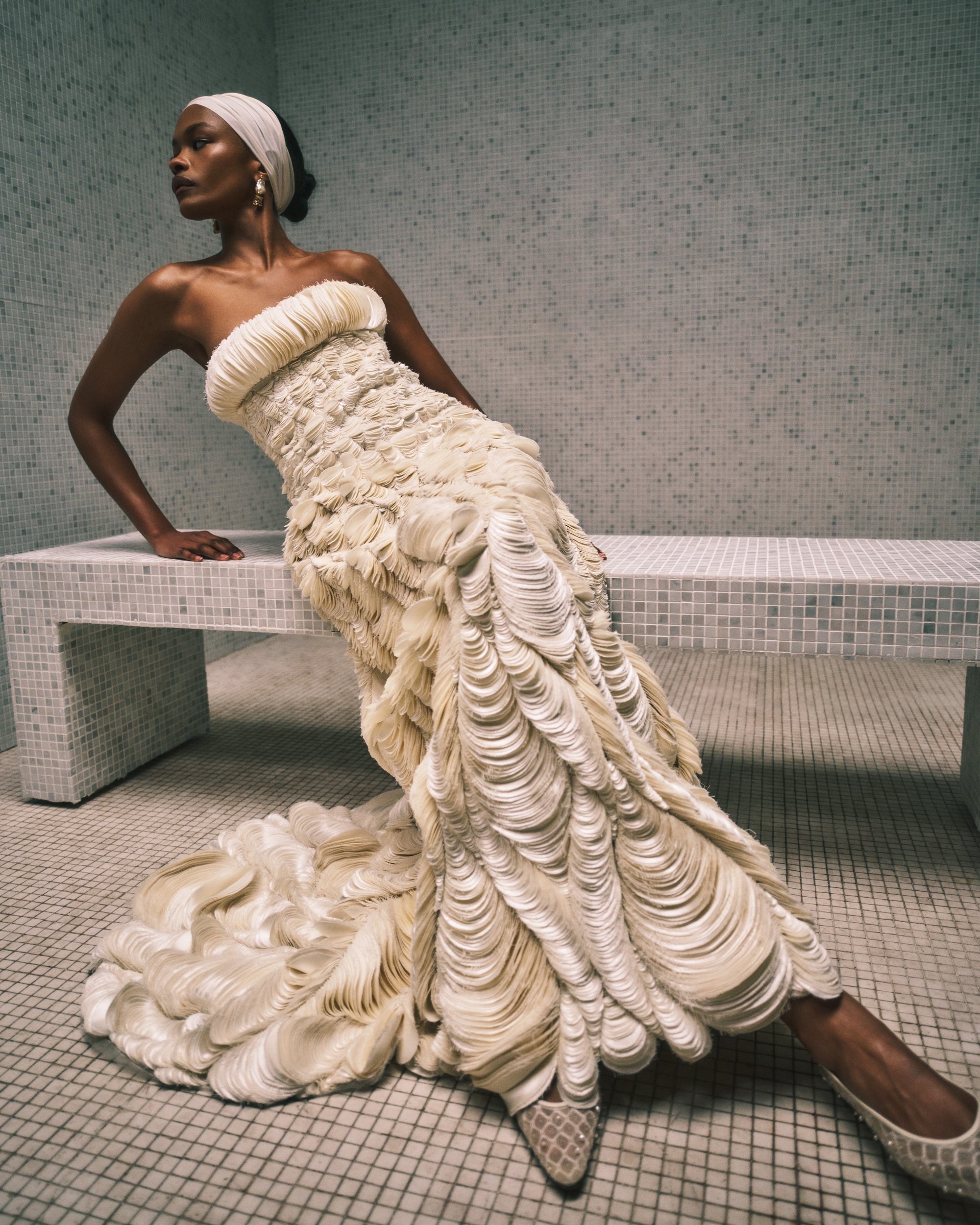 Strapless A-line empire waist gown decorated entirely with hand cut silk wool cascading petal embroidery. Thousands of hand applied silk wool petals undulate with texture throughout the gown falling into a train at back. Boned internal bustier, internal grosgrain belt and invisible zip closure at center back.
