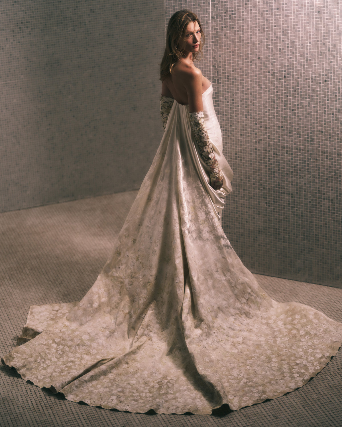 Floral hand painted silk wool twill strapless column gown. Fluid silk wool drape falls from center front and wraps the hip transcending into a watteau at center back. Removable train is scattered with hand painted florals throughout. Boned internal bustier, internal grosgrain belt and invisible zip closure at center back.