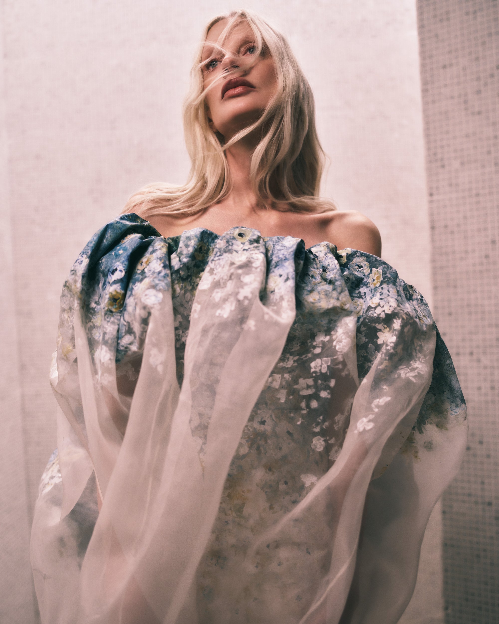 Floral degrade hand painted silk wool twill column gown with exaggerated flared neckline layered with hand painted transparent silk organza tapered bubbled overlay. Boned internal bustier, internal grosgrain belt and invisible zip closure at center back.