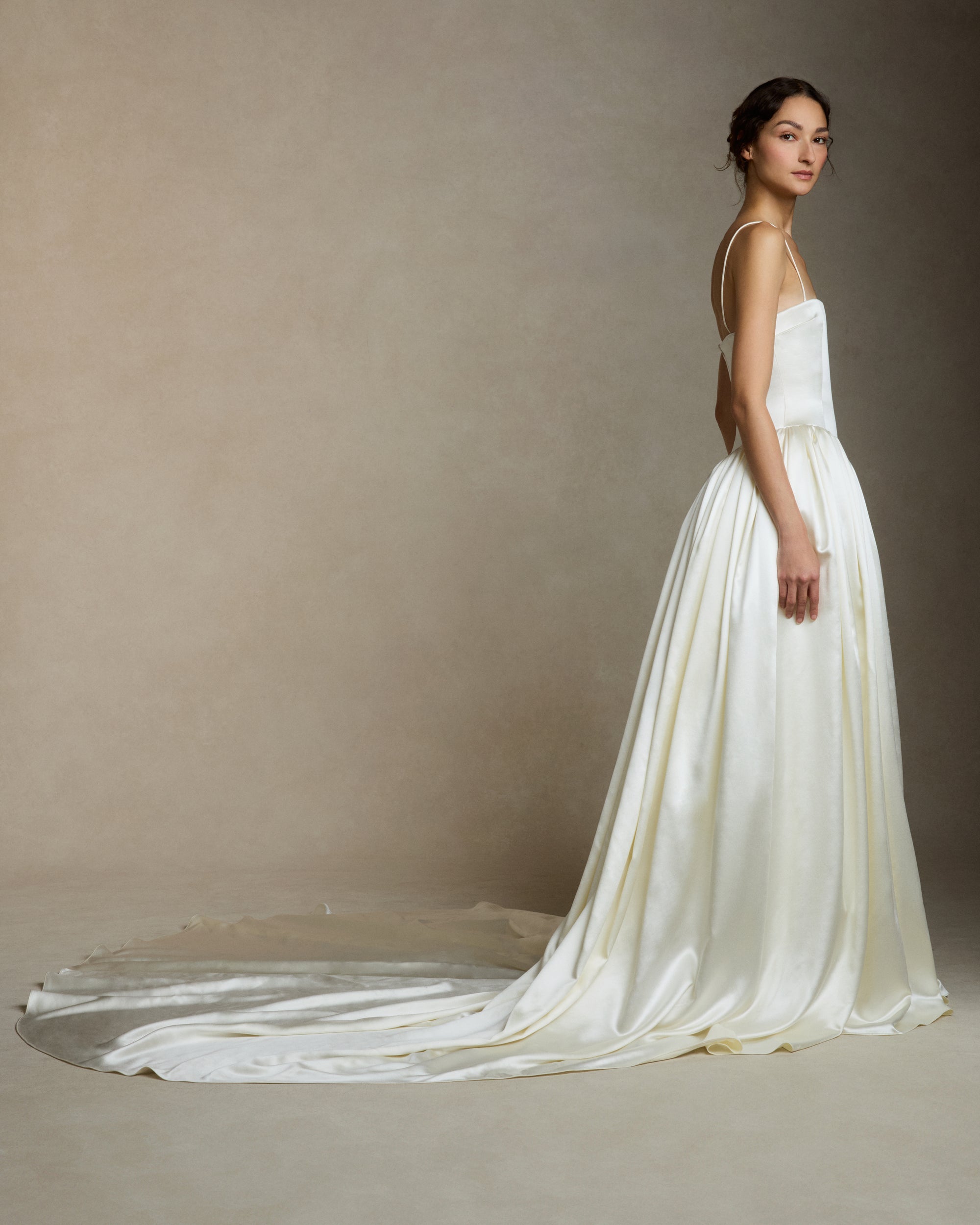 Silk wool straight neck ballgown with dramatic basque waist. Structured sculpted bodice is suspended from delicate spaghetti straps. Gathered waist full ball skirt is finished with baby hem. Boned internal bustier, internal grosgrain belt and invisible zip closure at center back.