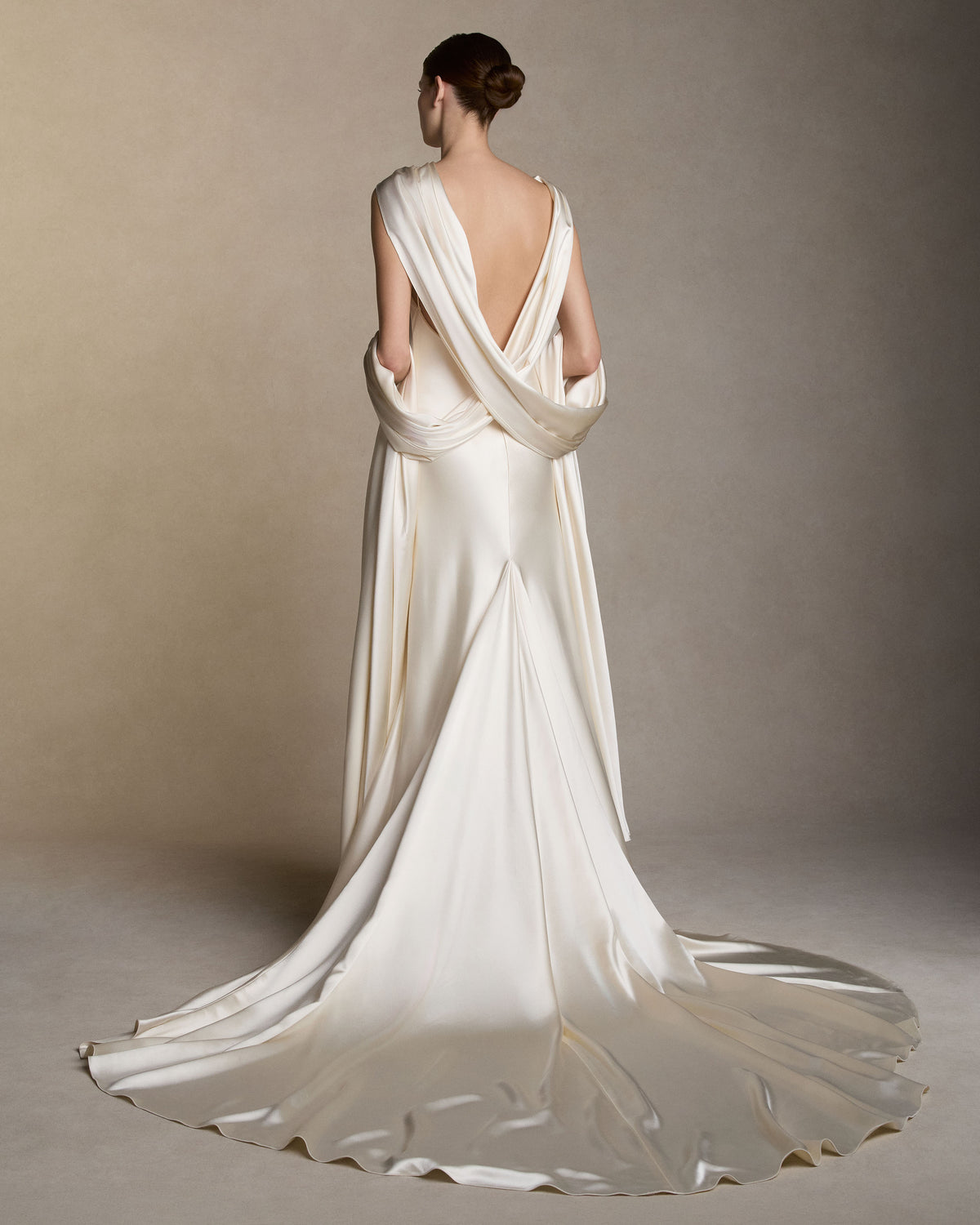 Silk satin slip dress with an asymmetric scarf drape knotted at the strap, falling across the shoulders into a shawl train at the back. Invisible zip closure at center back. 