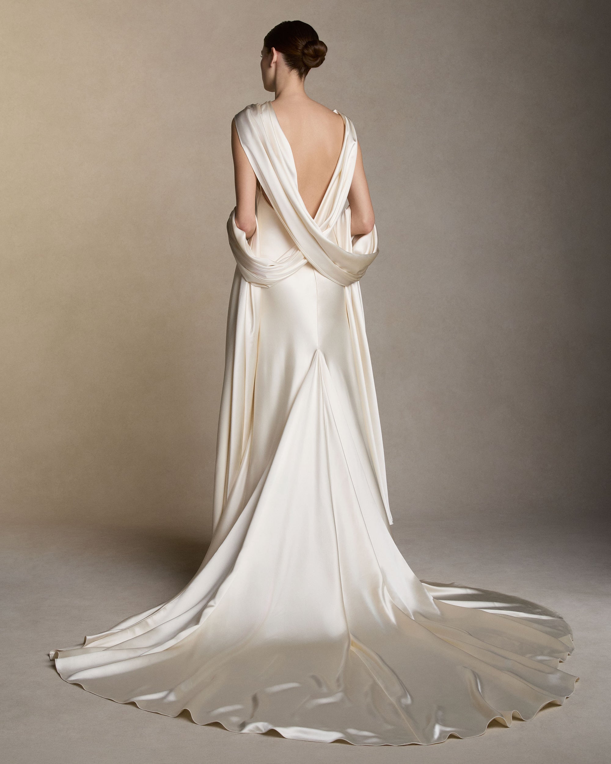 Silk satin slip dress with an asymmetric scarf drape knotted at the strap, falling across the shoulders into a shawl train at the back. Invisible zip closure at center back. 