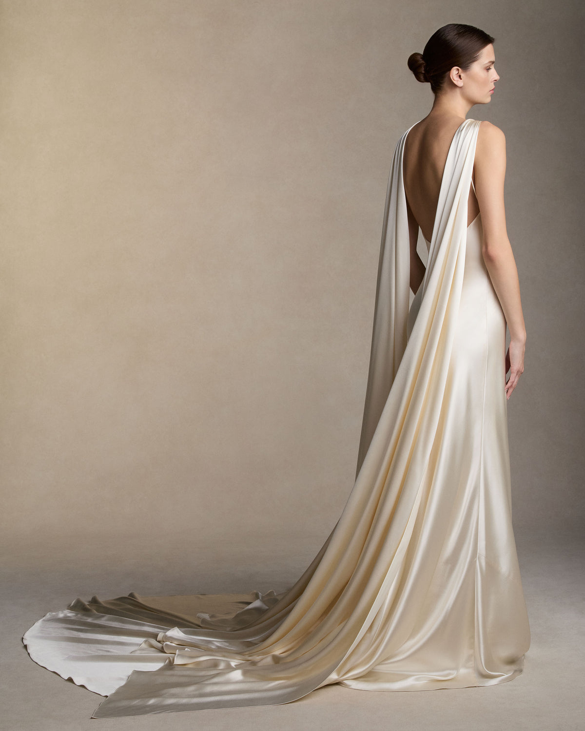 Silk satin slip dress with an asymmetric scarf drape knotted at the strap, falling across the shoulders into a shawl train at the back. Invisible zip closure at center back. 