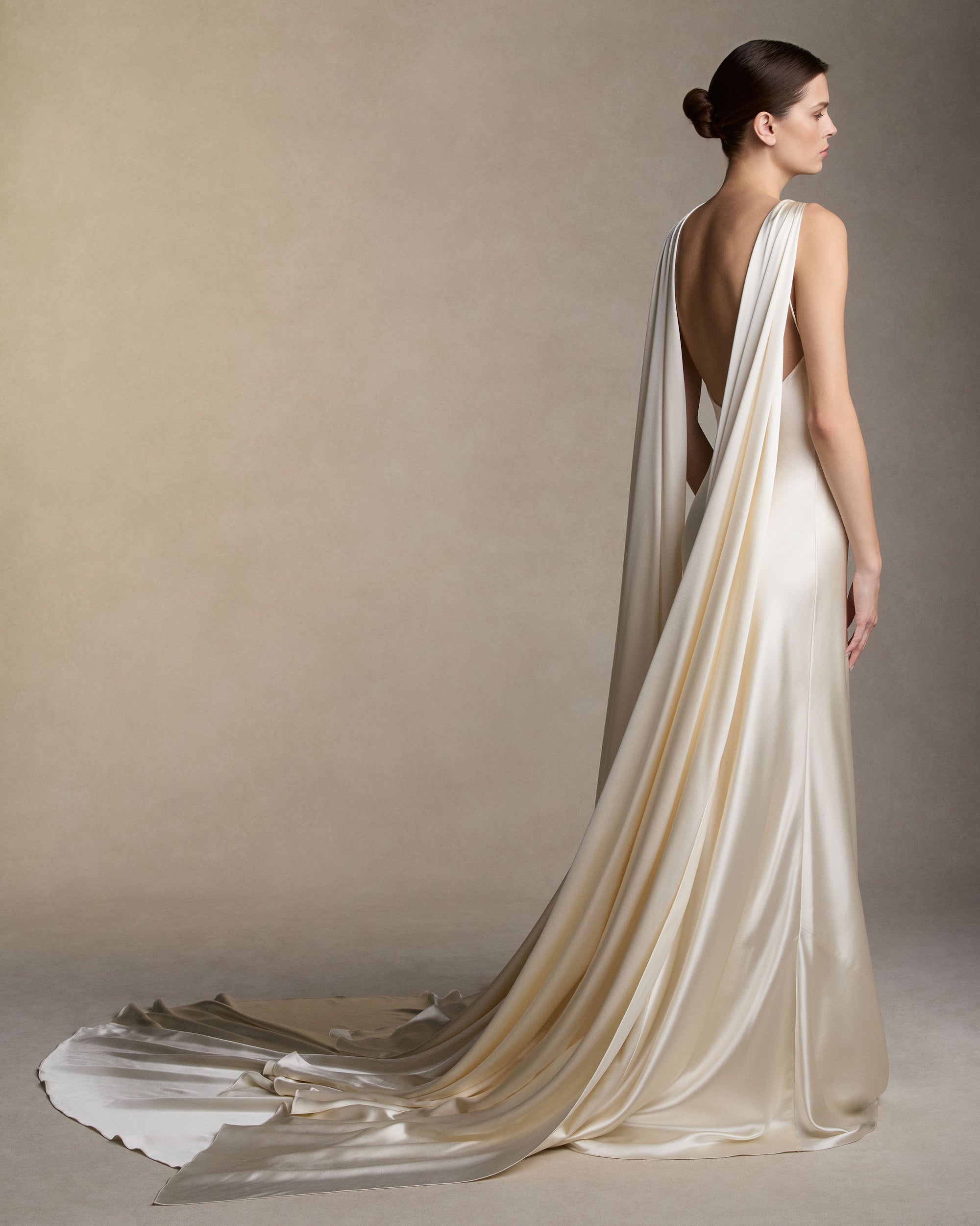 Silk satin slip dress with an asymmetric scarf drape knotted at the strap, falling across the shoulders into a shawl train at the back. Invisible zip closure at center back. 