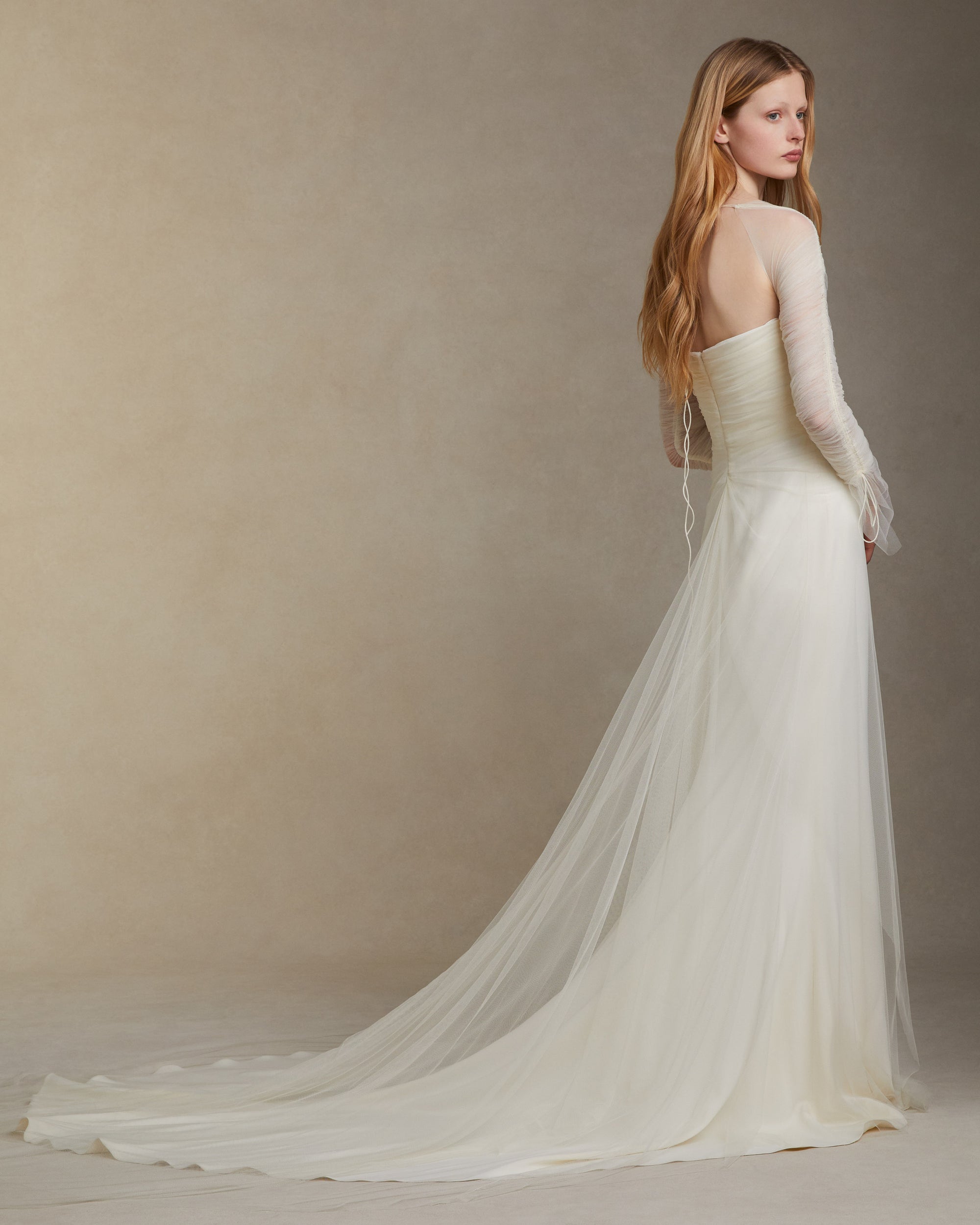 Stretch cady gown with draped soft tulle overlay. Gathered soft tulle sleeves with spaghetti tie detail resolve into a tie closure at back neck. Center back invisible zip.