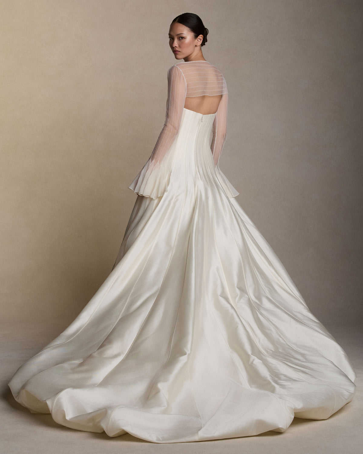 Strapless silk wool twill ballgown with a dramatic train. Rows of grosgrain boning detail shape the bodice and disperse into undulating panels, finishing with a bubble hem. Boned internal bustier, internal grosgrain belt and invisible zip closure at center back.Styled with Lulu topper