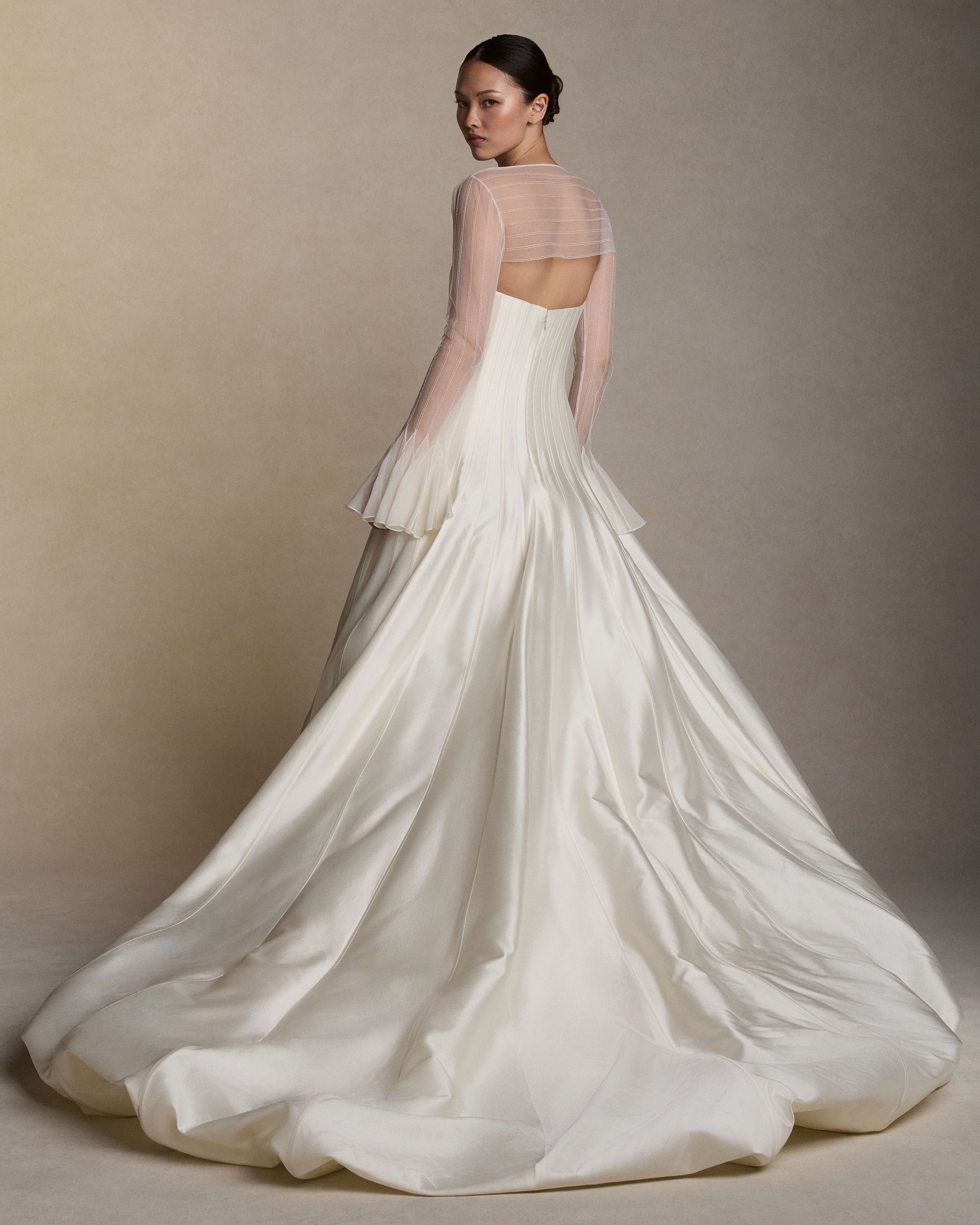 Strapless silk wool twill ballgown with a dramatic train. Rows of grosgrain boning detail shape the bodice and disperse into undulating panels, finishing with a bubble hem. Boned internal bustier, internal grosgrain belt and invisible zip closure at center back.Styled with Lulu topper