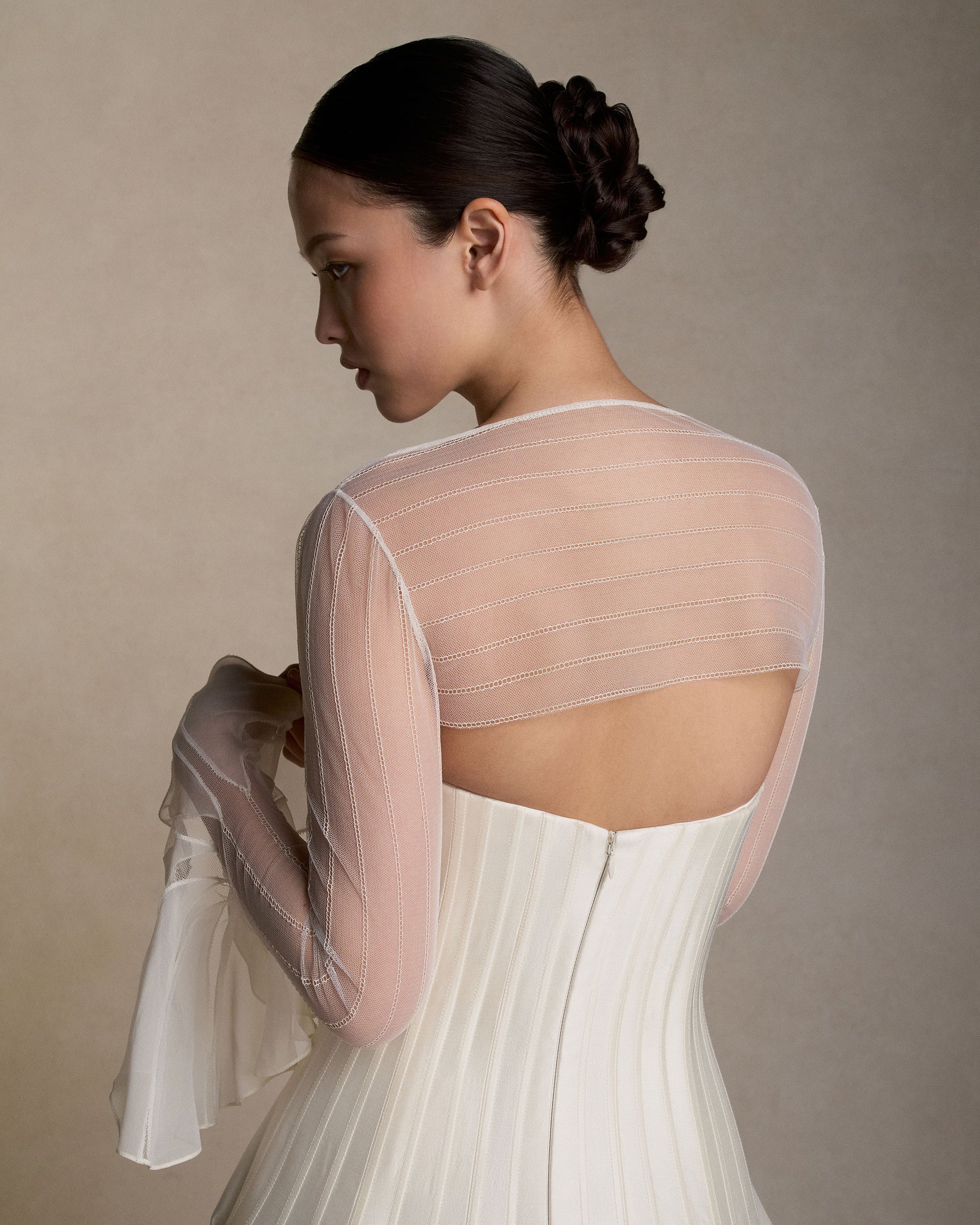Strapless silk wool twill ballgown with a dramatic train. Rows of grosgrain boning detail shape the bodice and disperse into undulating panels, finishing with a bubble hem. Boned internal bustier, internal grosgrain belt and invisible zip closure at center back.Styled with Lulu topper