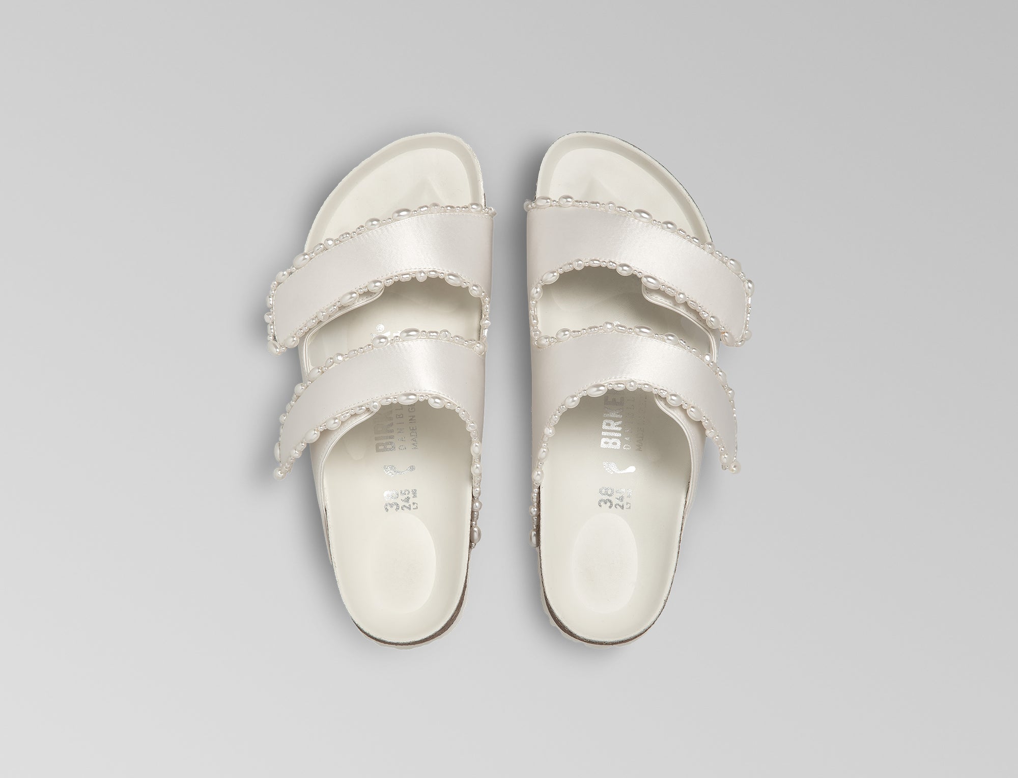 The Arizona is elevated in luminous ivory satin with piped trim detail, accented with delicate pearl edging for a refined and ceremonial finish. The design also introduces an innovative adjustable hidden buckle closure. Handcrafted in Germany, the shoe blends BIRKENSTOCK’s iconic comfort with Danielle Frankel’s bridal elegance.- Upper: Delicate satin upper material- Footbed: Anatomical shaped BIRKENSTOCK cork latex Footbed lined with premium Nappa Leather- Sole: EVA die cut outsole with a custom design, blending classic BIRKENSTOCK bone pattern with delicate lace inspired detailing