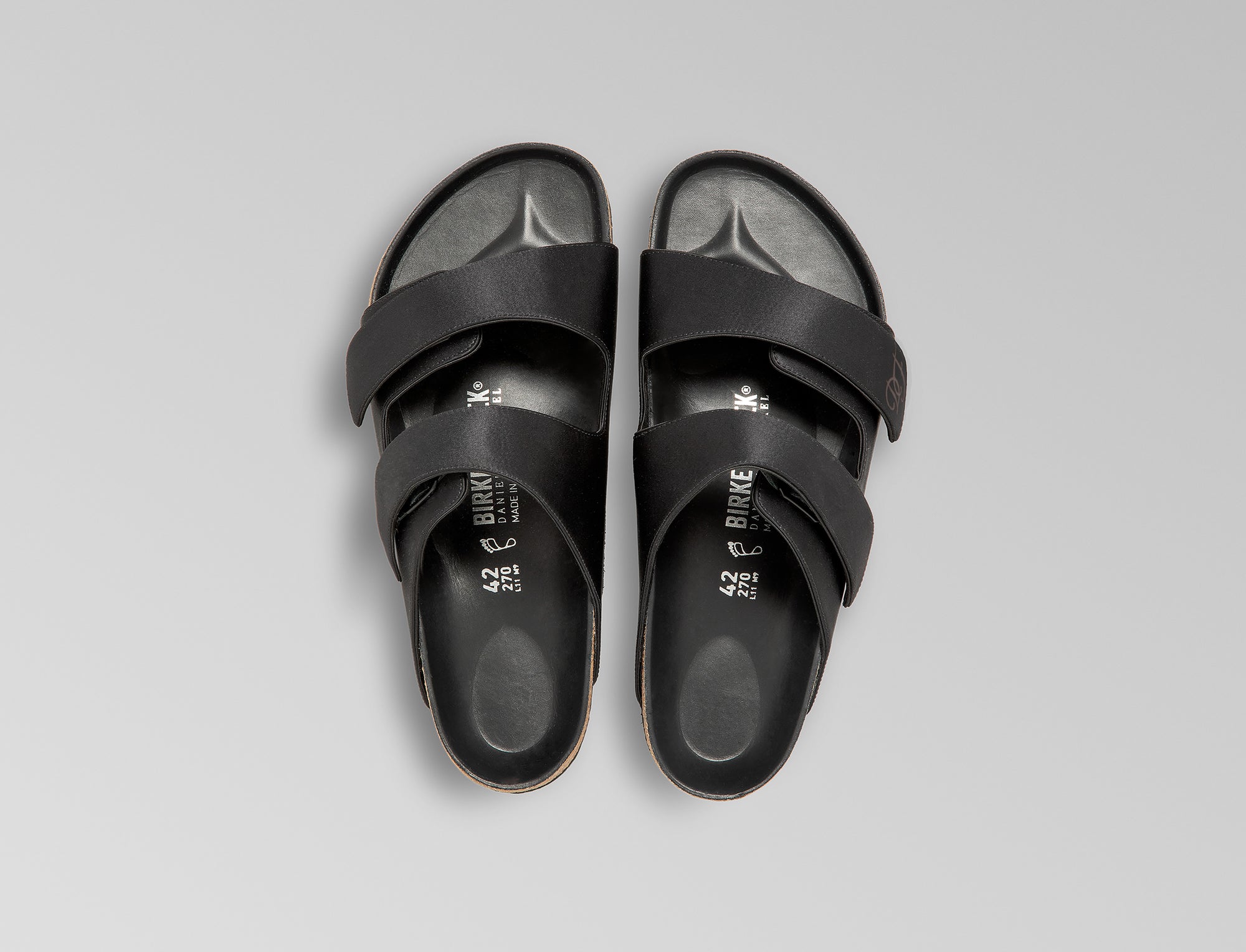 The Arizona takes a sleek turn in black satin, offering a modern, unisex design perfect for any elegant event. The design also introduces an innovative adjustable hidden buckle closure. Expertly crafted in Germany, the shoe pairs the signature BIRKENSTOCK comfort with understated sophistication through Danielle Frankel design touch. - Upper: Delicate satin upper, piped trim edge detail for premium tuxedo like finish- Footbed: Anatomical shaped BIRKENSTOCK cork latex Footbed lined with premium Nappa Leather- Sole: EVA die cut outsole with a custom design, blending classic BIRKENSTOCK bone pattern with delicate leaf inspired detailing 