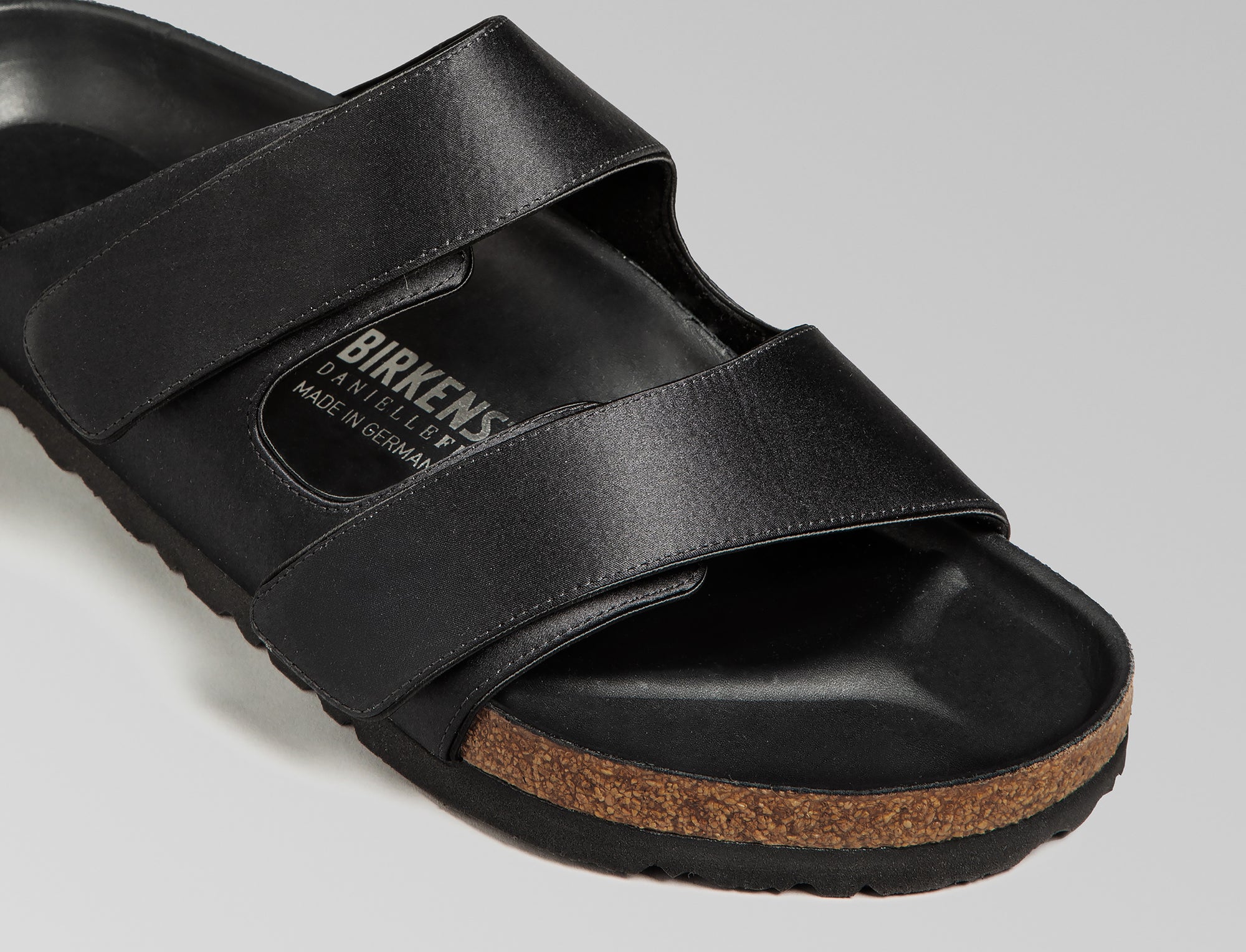 The Arizona takes a sleek turn in black satin, offering a modern, unisex design perfect for any elegant event. The design also introduces an innovative adjustable hidden buckle closure. Expertly crafted in Germany, the shoe pairs the signature BIRKENSTOCK comfort with understated sophistication through Danielle Frankel design touch. - Upper: Delicate satin upper, piped trim edge detail for premium tuxedo like finish- Footbed: Anatomical shaped BIRKENSTOCK cork latex Footbed lined with premium Nappa Leather- Sole: EVA die cut outsole with a custom design, blending classic BIRKENSTOCK bone pattern with delicate leaf inspired detailing 