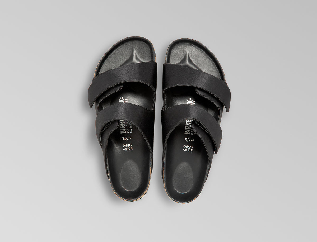 The Arizona takes a sleek turn in black satin, offering a modern, unisex design perfect for any elegant event. The design also introduces an innovative adjustable hidden buckle closure. Expertly crafted in Germany, the shoe pairs the signature BIRKENSTOCK comfort with understated sophistication through Danielle Frankel design touch. - Upper: Delicate satin upper, piped trim edge detail for premium tuxedo like finish- Footbed: Anatomical shaped BIRKENSTOCK cork latex Footbed lined with premium Nappa Leather- Sole: EVA die cut outsole with a custom design, blending classic BIRKENSTOCK bone pattern with delicate leaf inspired detailing 