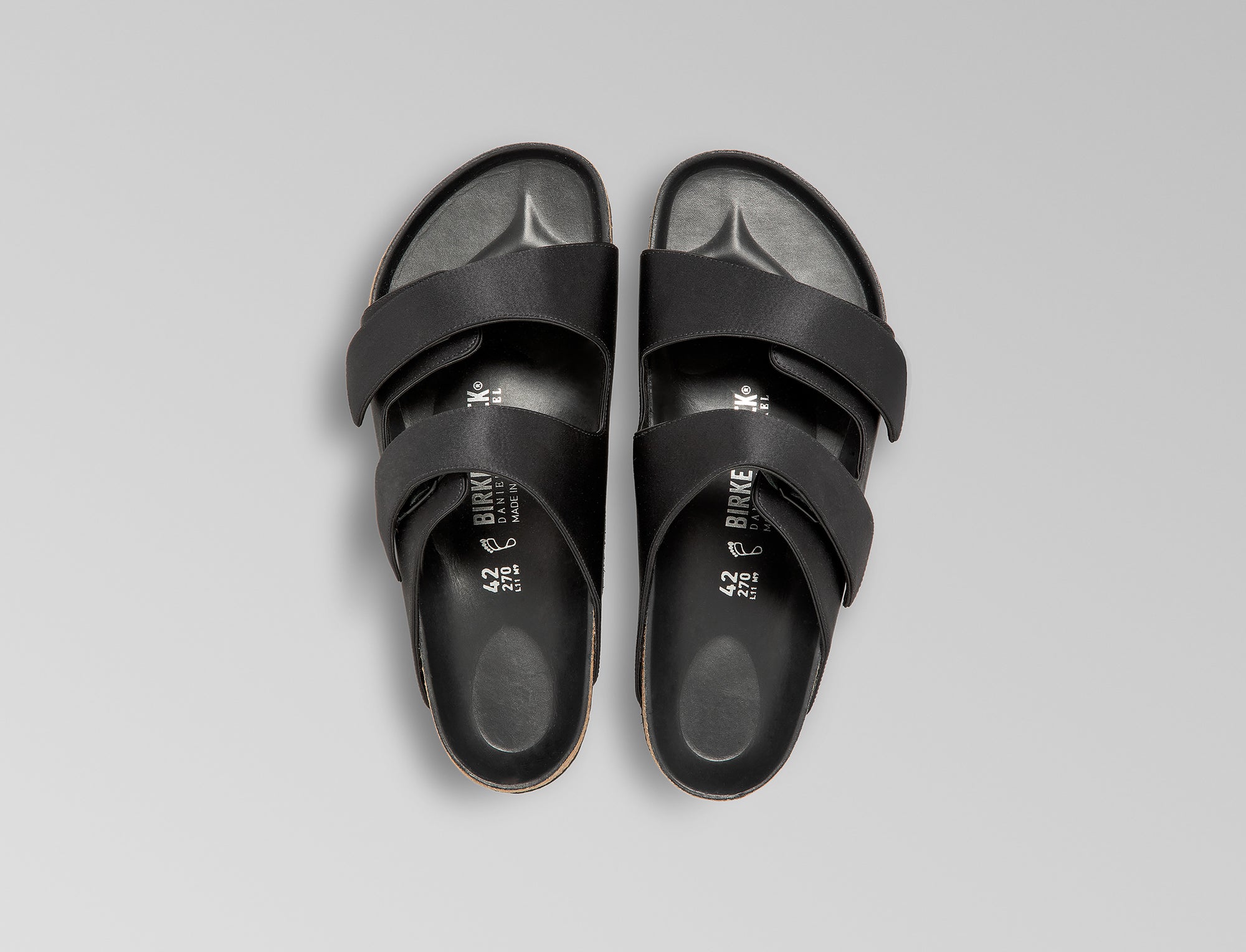 The Arizona takes a sleek turn in black satin, offering a modern, unisex design perfect for any elegant event. The design also introduces an innovative adjustable hidden buckle closure. Expertly crafted in Germany, the shoe pairs the signature BIRKENSTOCK comfort with understated sophistication through Danielle Frankel design touch. - Upper: Delicate satin upper, piped trim edge detail for premium tuxedo like finish- Footbed: Anatomical shaped BIRKENSTOCK cork latex Footbed lined with premium Nappa Leather- Sole: EVA die cut outsole with a custom design, blending classic BIRKENSTOCK bone pattern with delicate leaf inspired detailing 