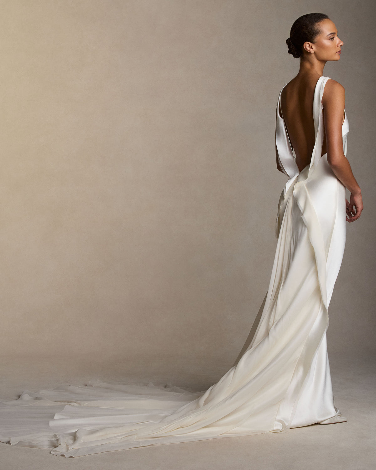 Silk wool high neck bias cut gown. Bias silk wool and chiffon trims decorates the neckline falling down back and finishing into diagonal skirt seams. Full chiffon godet overlay at center back releases into train. Invisible zip closure at center back.