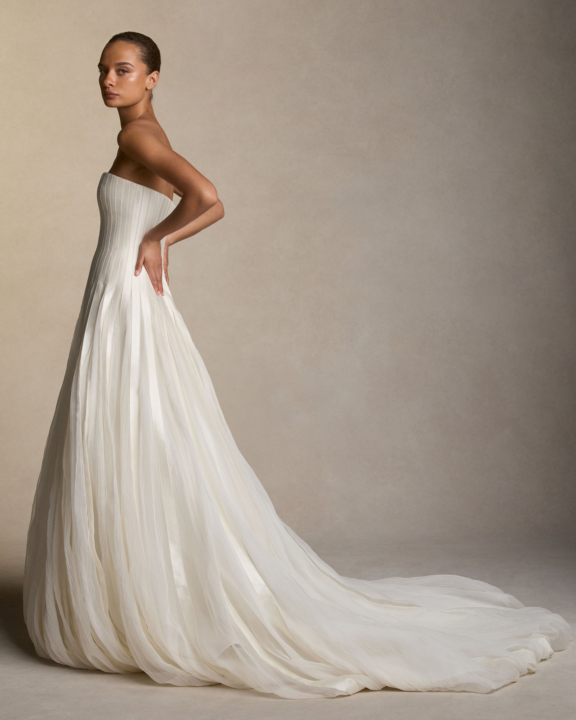 Silk wool twill and crinkle organza godet ball gown. Intricate seamed construction shapes the bodice and releases into crinkle organza godets creating a full ball skirt. Boned internal bustier with internal grosgrain waistbelt and  invisible zip closure at center back. 