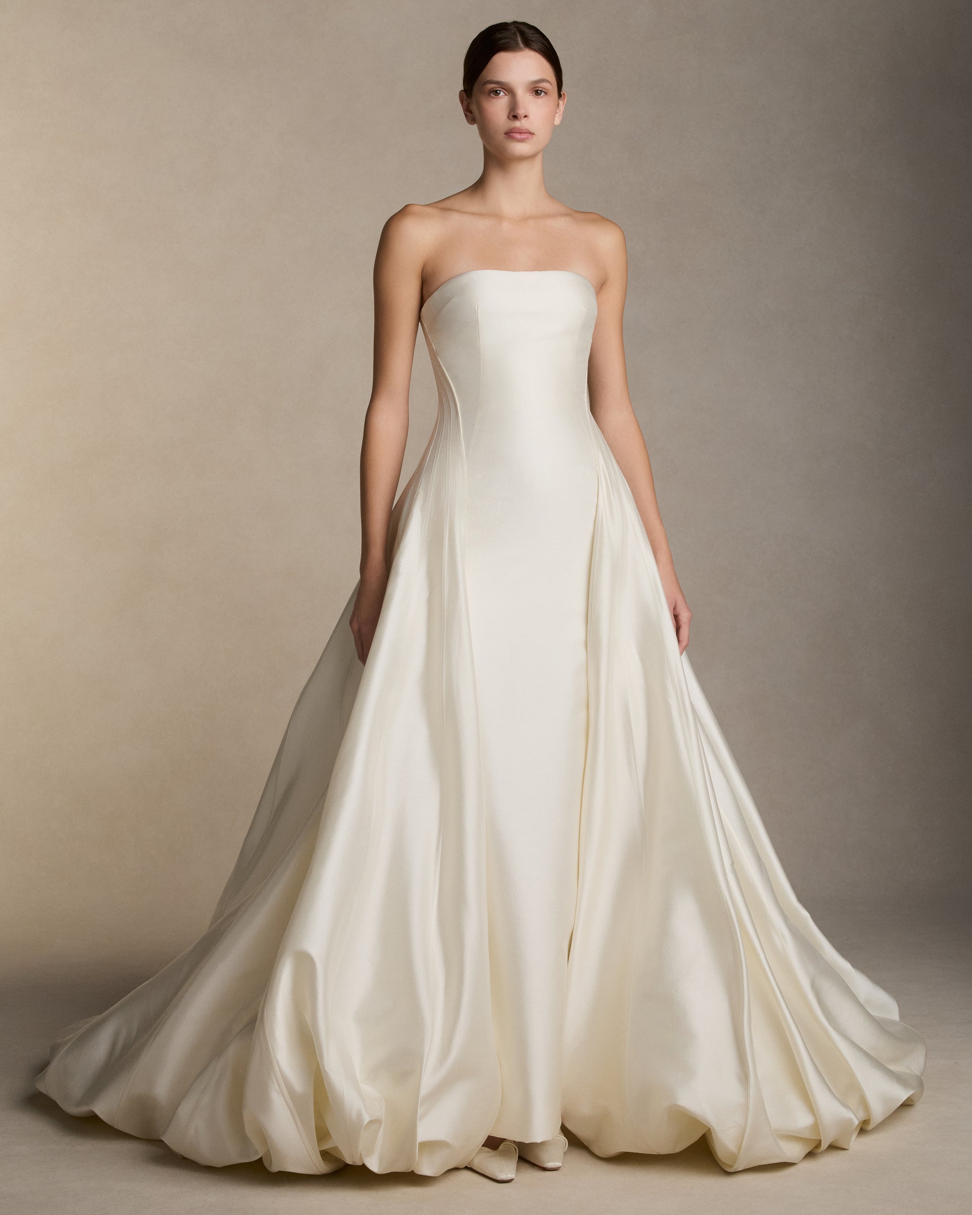 Silk wool twill column gown with dramatic ball skirt. Shaped boning accentuates the waist and falls into a bubble train. Invisible zip closure at center back.