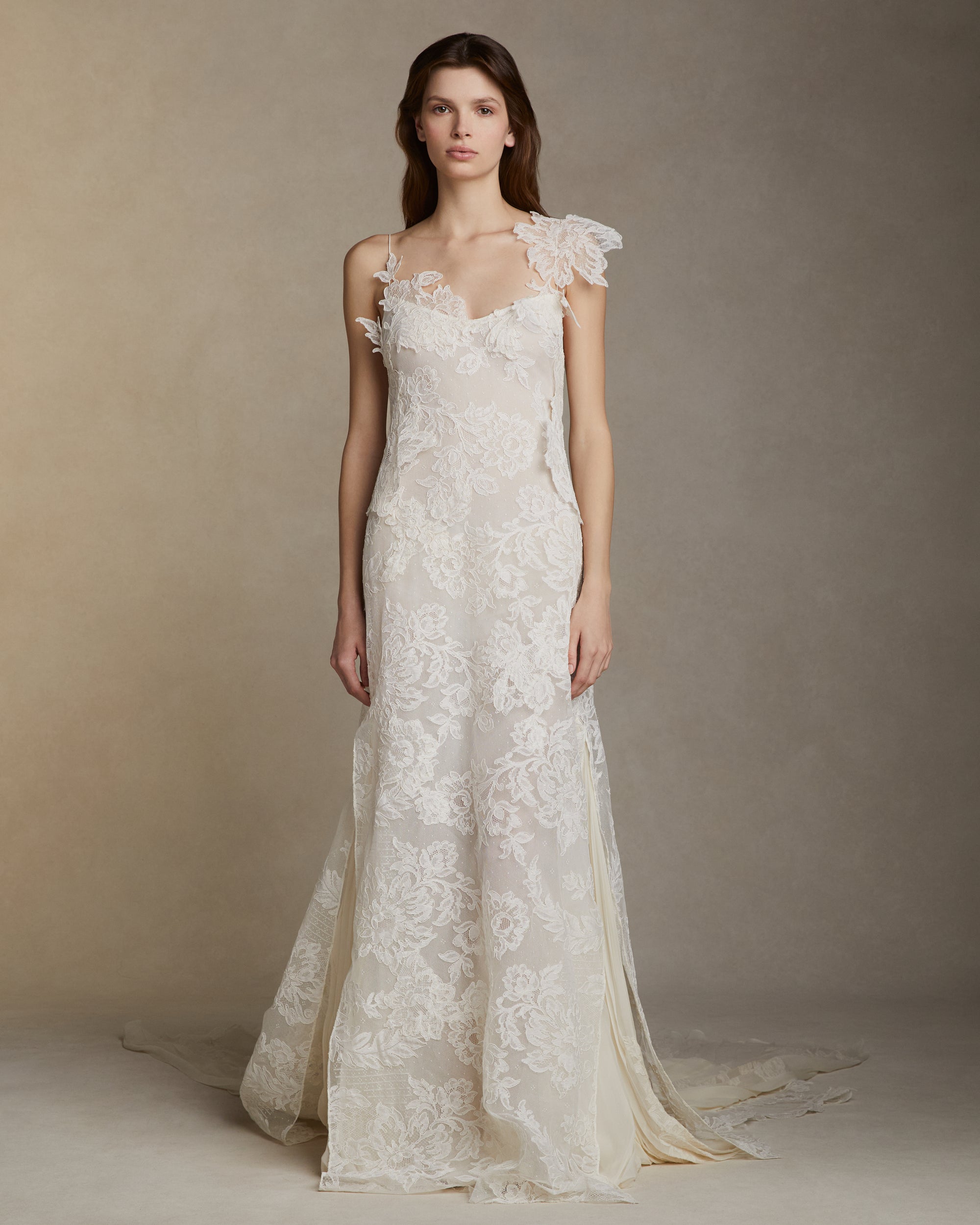 Lyon lace gown with pleated chiffon godets and hand cut Lyon lace applique throughout. Hand cut lace adorns the spaghetti straps and watteau peels from center back releasing into an extended pleated chiffon train. Soft internal bustier. Invisible zip closure at center back.