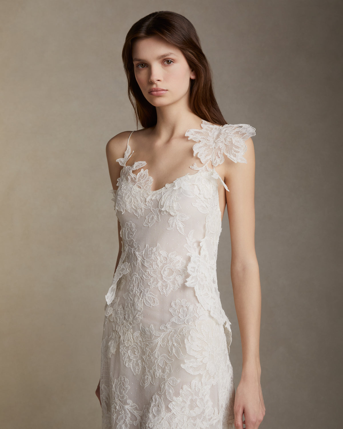 Lyon lace gown with pleated chiffon godets and hand cut Lyon lace applique throughout. Hand cut lace adorns the spaghetti straps and watteau peels from center back releasing into an extended pleated chiffon train. Soft internal bustier. Invisible zip closure at center back.