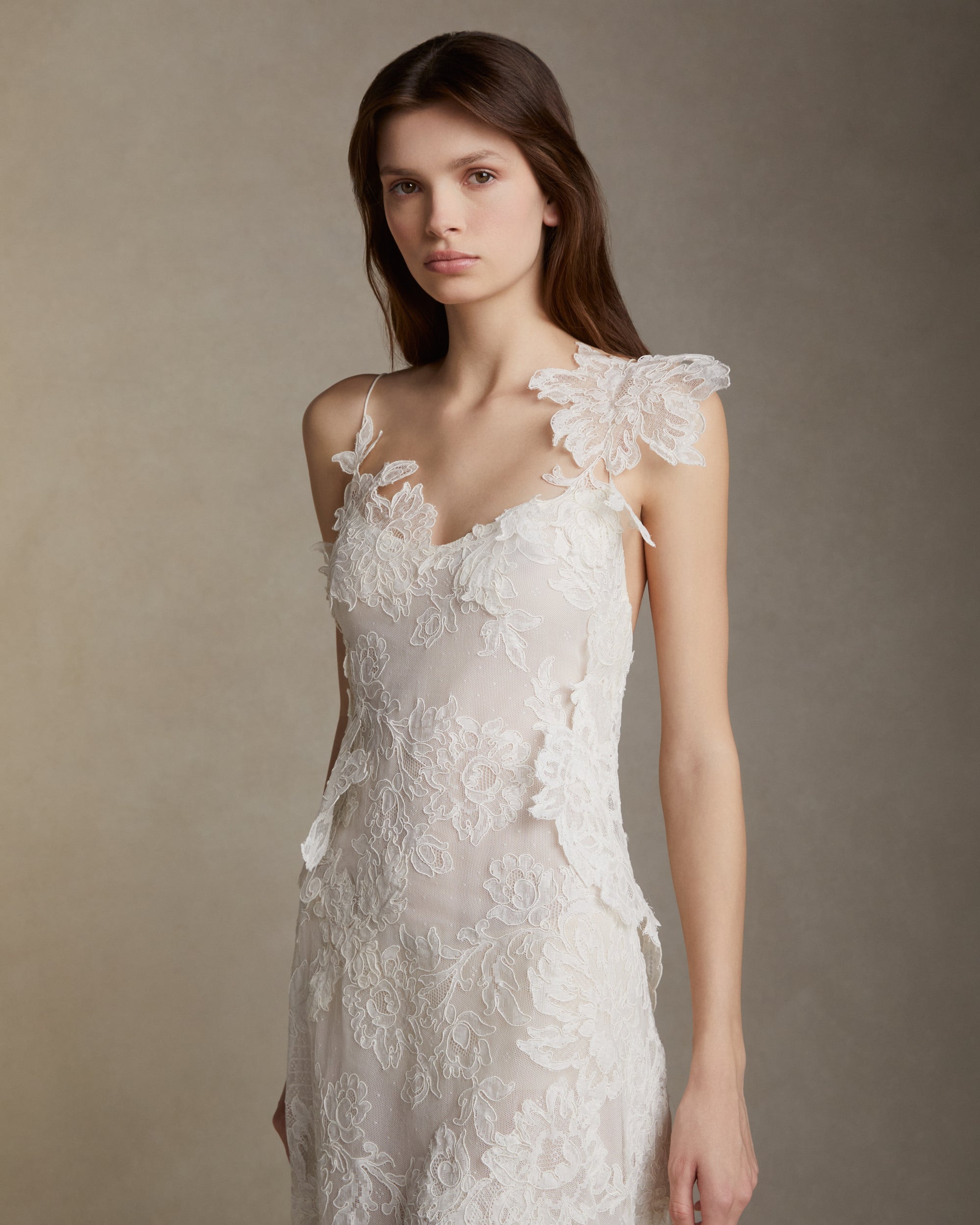 Lyon lace gown with pleated chiffon godets and hand cut Lyon lace applique throughout. Hand cut lace adorns the spaghetti straps and watteau peels from center back releasing into an extended pleated chiffon train. Soft internal bustier. Invisible zip closure at center back.