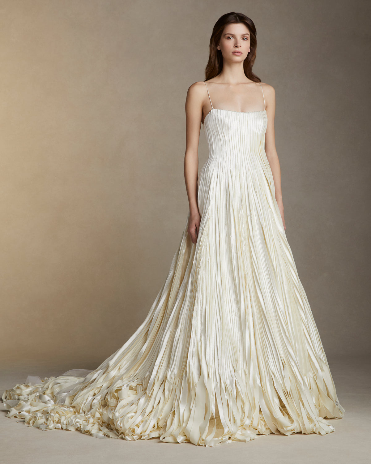Soft scoop neck ballgown decorated with hand cut and hand frayed bias silk wool strip fabric technique embroidery. Layers of silk wool bias cascade organically into a bubble hem train. Internal bustier with invisible zip closure at center back.