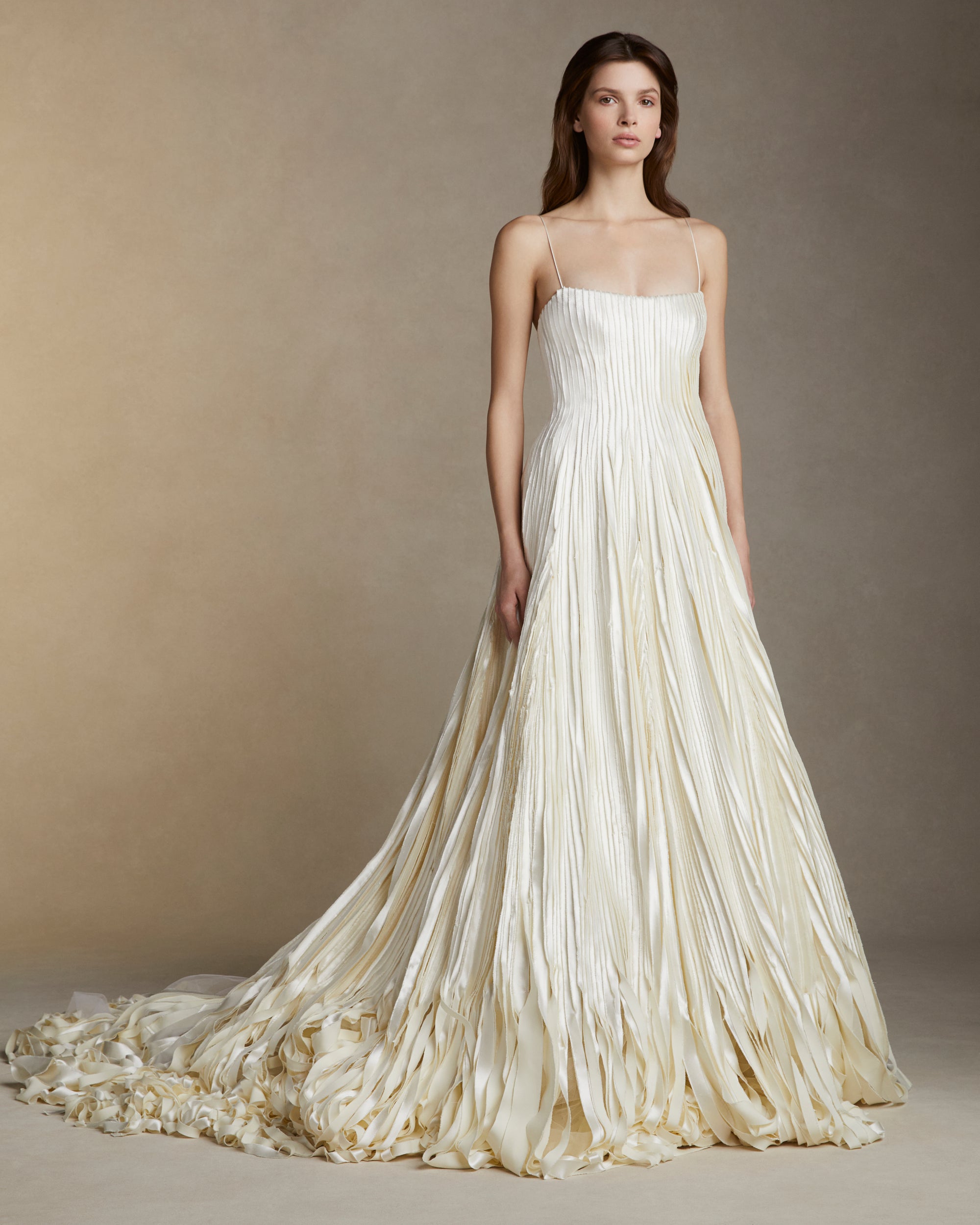 Soft scoop neck ballgown decorated with hand cut and hand frayed bias silk wool strip fabric technique embroidery. Layers of silk wool bias cascade organically into a bubble hem train. Internal bustier with invisible zip closure at center back.