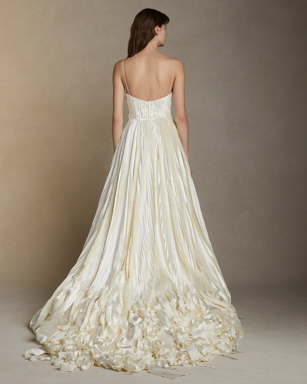Soft scoop neck ballgown decorated with hand cut and hand frayed bias silk wool strip fabric technique embroidery. Layers of silk wool bias cascade organically into a bubble hem train. Internal bustier with invisible zip closure at center back.