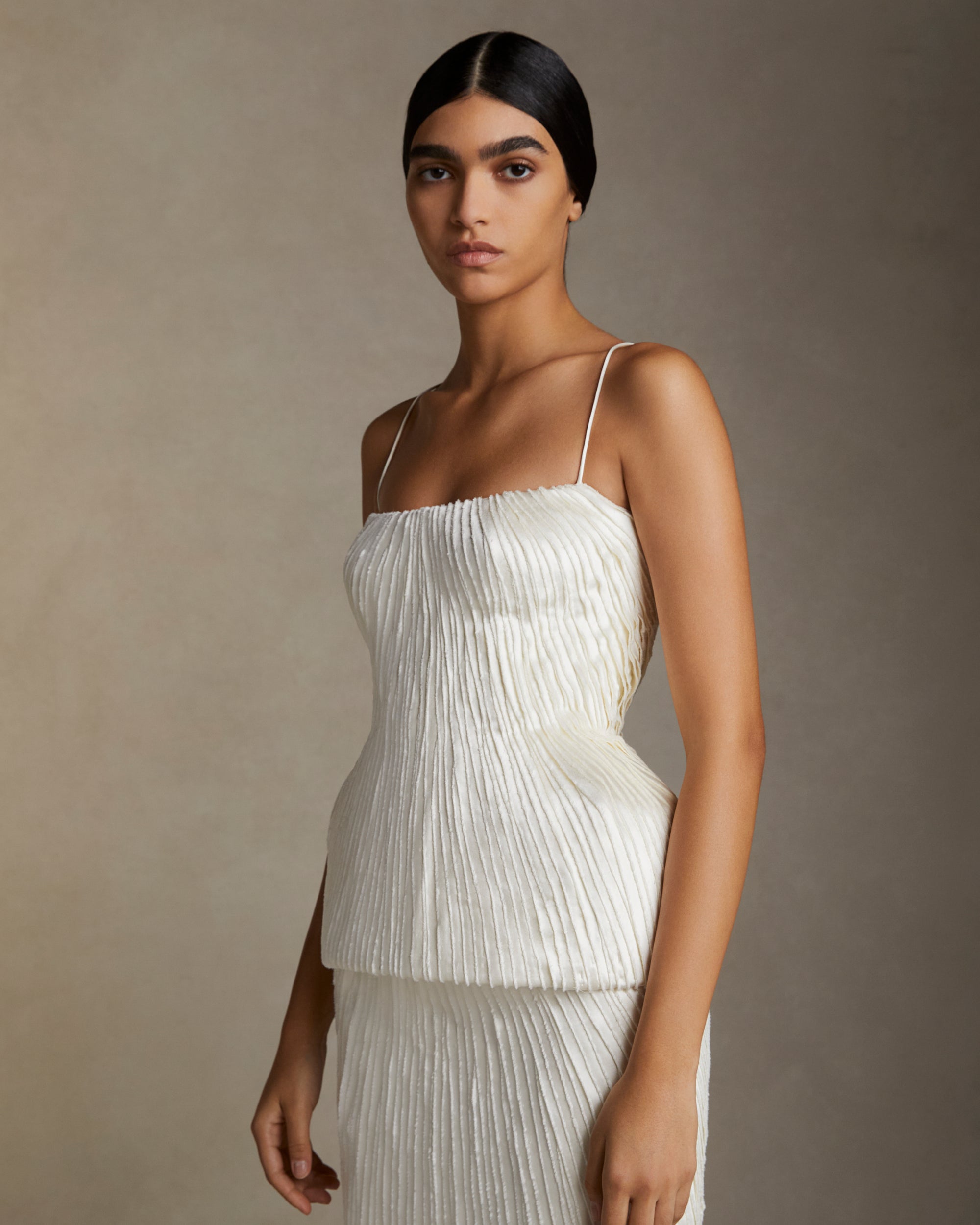 Scooped neck bustier decorated with hand cut and hand frayed bias silk wool strip fabric technique embroidery. Nipped waist and structured hip shape. Separating zipper closure at center back.Styled with ﻿Gia skirt