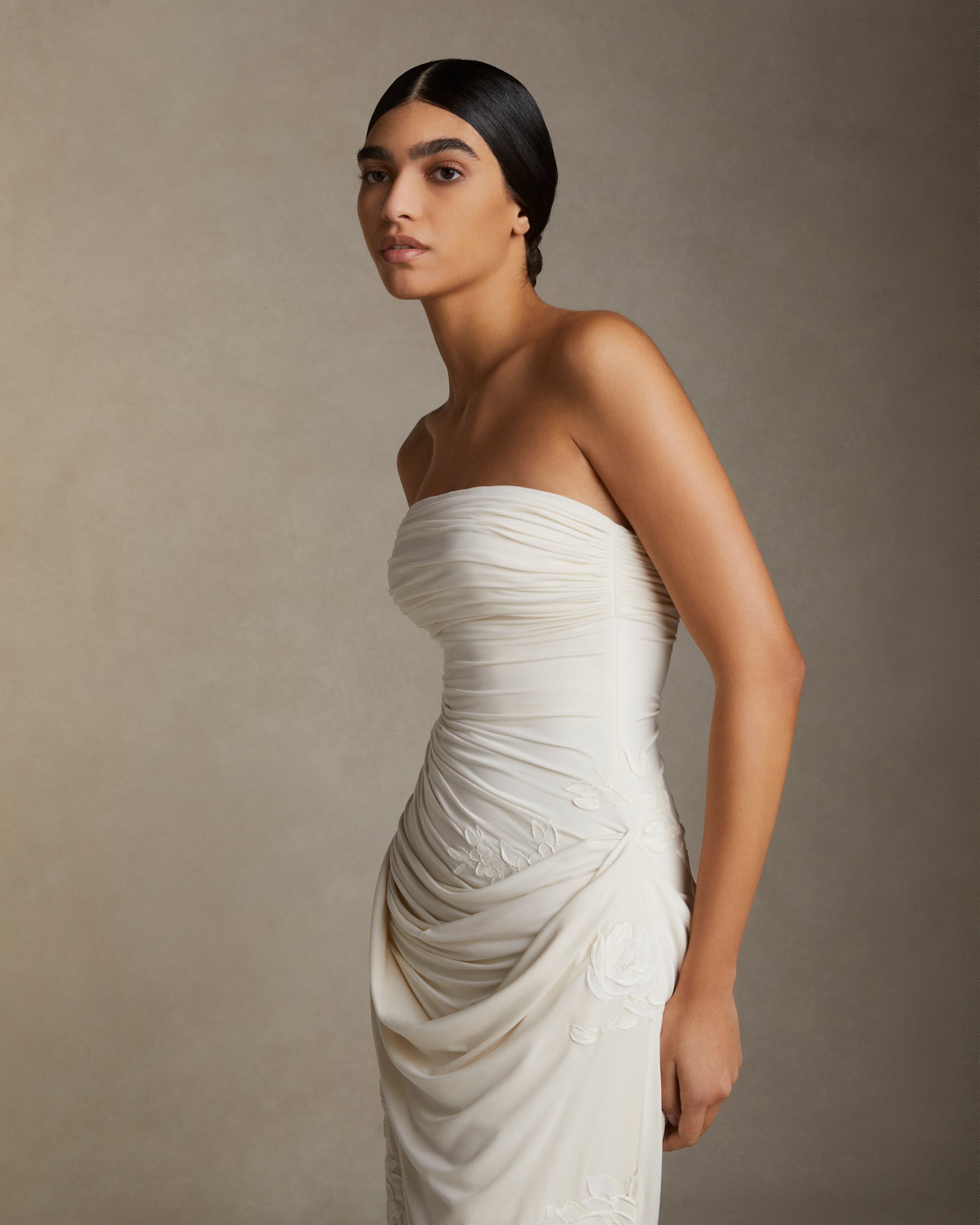 Fluid jersey strapless gown with asymmetric cascading drape and hand painted floral motifs throughout. Puddle train detail. Invisible zip closure at center back.