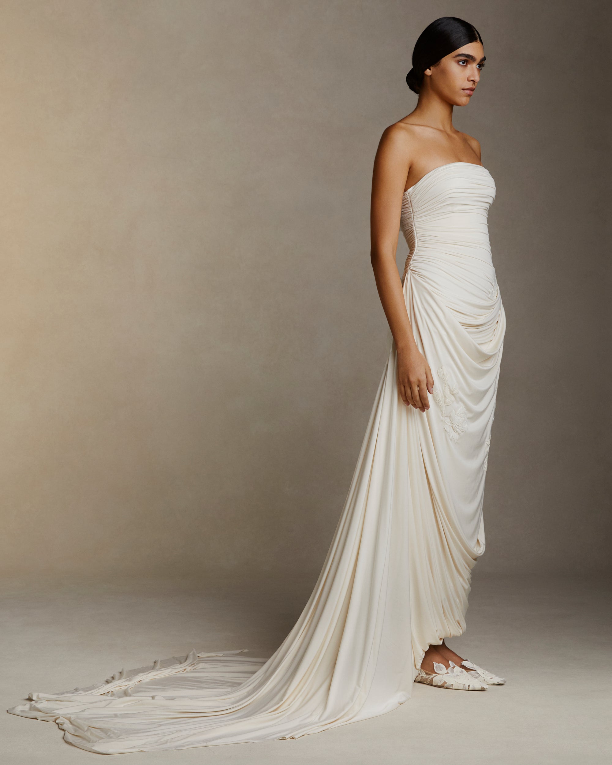 Fluid jersey strapless gown with asymmetric cascading drape and hand painted floral motifs throughout. Puddle train detail. Invisible zip closure at center back.