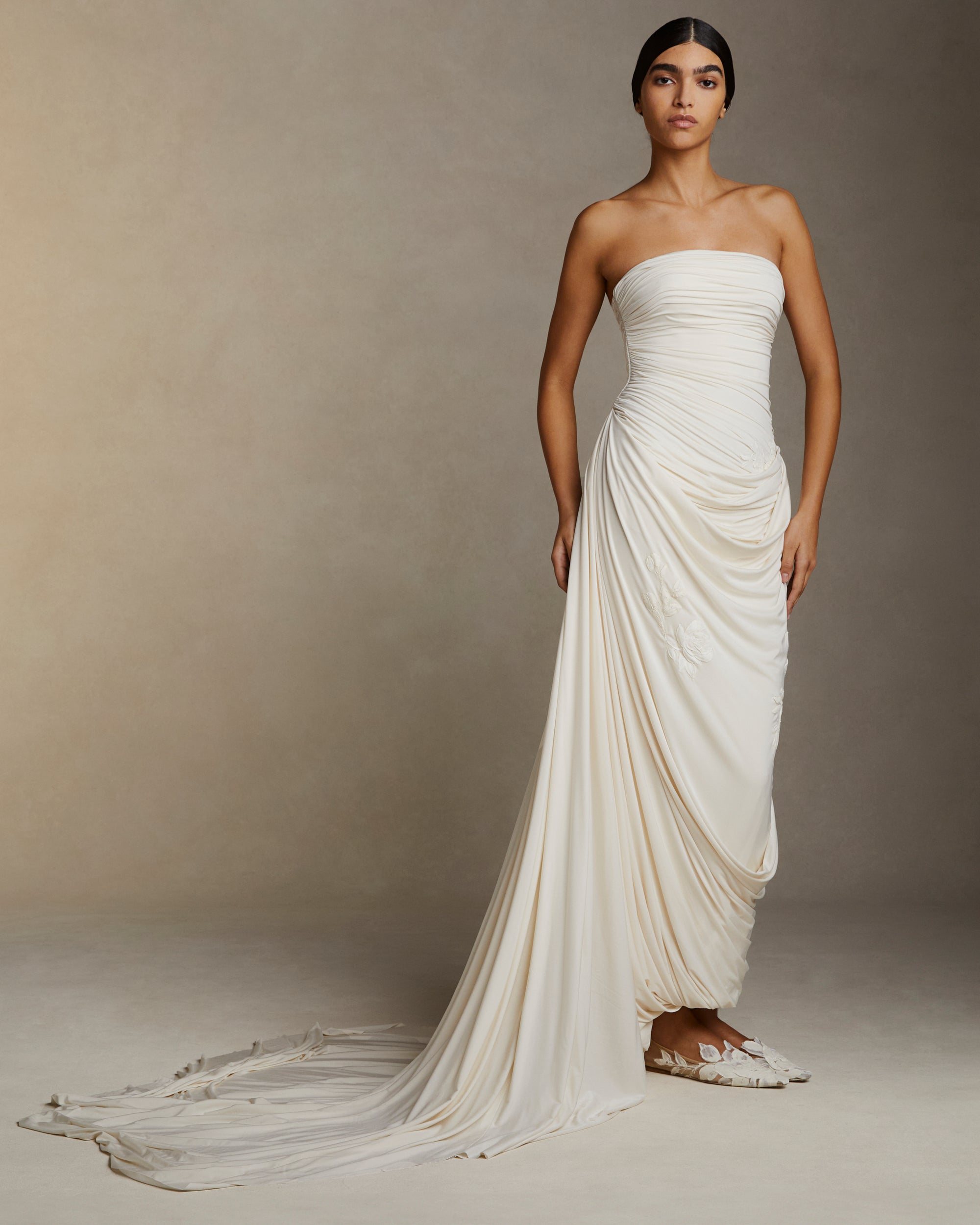 Fluid jersey strapless gown with asymmetric cascading drape and hand painted floral motifs throughout. Puddle train detail. Invisible zip closure at center back.