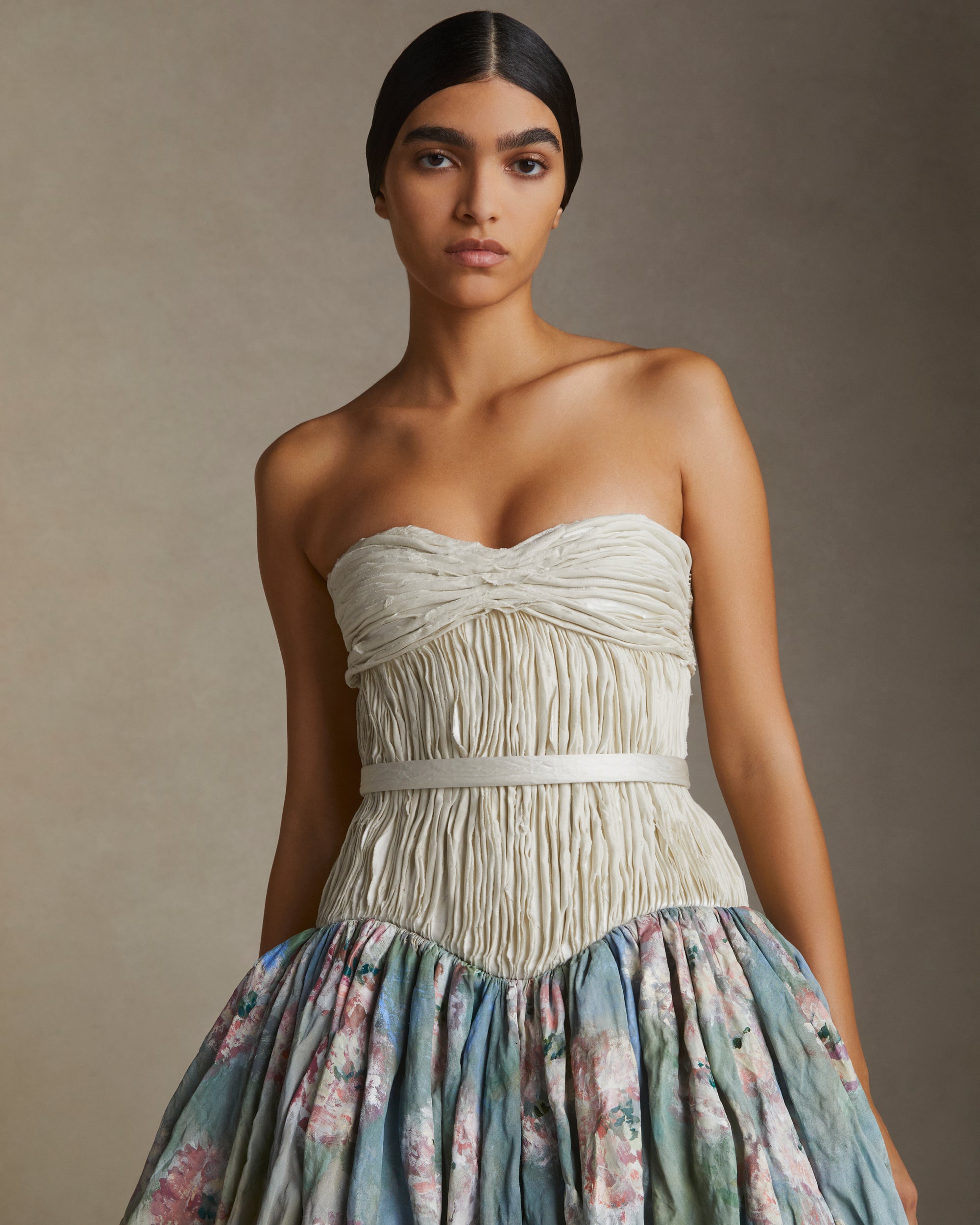 Strapless silk metal gown with hand painted florals that softly degrade down the lightly textured bubble hem skirt. Hand cut bias strip fabric technique decorates the bodice. Invisible zip closure at center back. Sold with self fabric belt. Available without hand painting as well, inquire atelier@daniellefrankelstudio.com for pricing