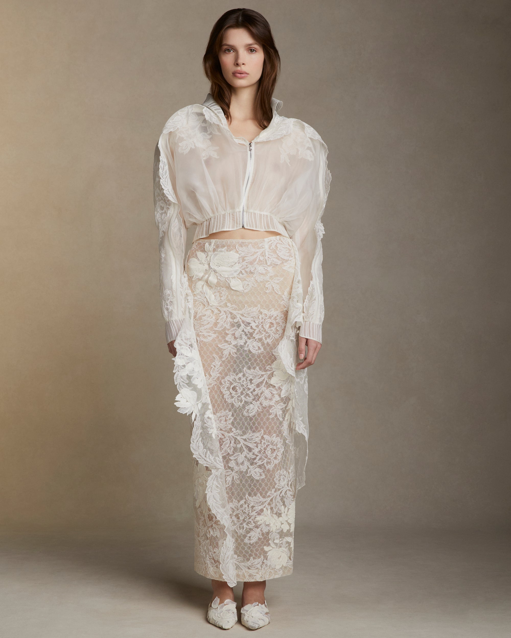 Lyon lace skirt framed in silk honeycomb netting with asymmetric flanges peeling away at the sides. Hand painted florals throughout. Invisible zip closure at center back.Styled with Marcel jacket