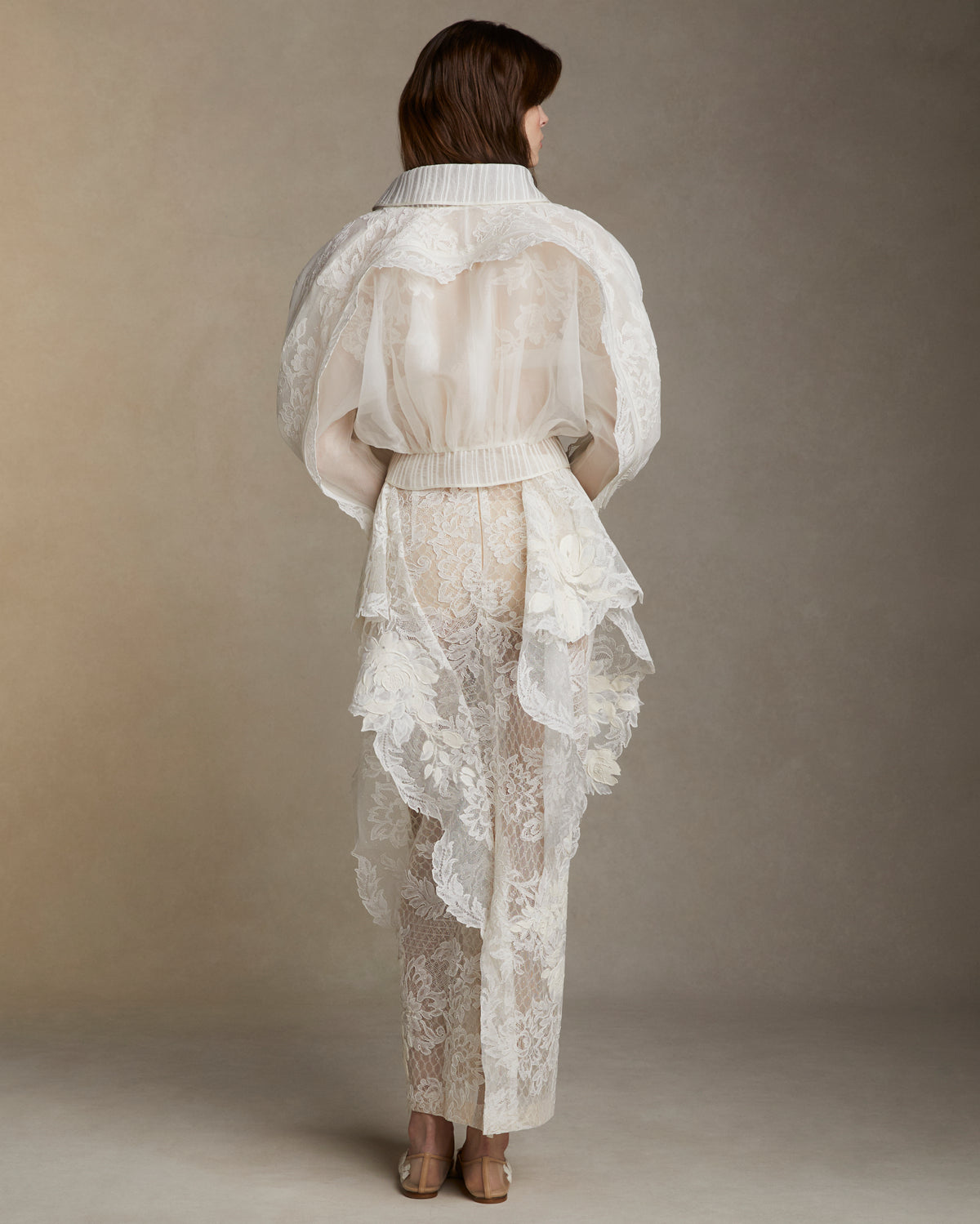 Silk organza jacket adorned with Lyon lace appliques. Lyon lace trim peeks out of a piped organza trimmed yoke. Separating zip closure at center front.Styled with Laila skirt