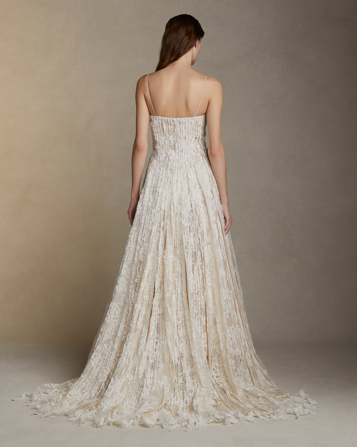 Soft scoop neck ballgown decorated with hand cut Lyon lace strip fabric technique. Layers of Lyon lace strips cascade organically into a released bubble hem train. Internal bustier and invisible zip closure at center back.
