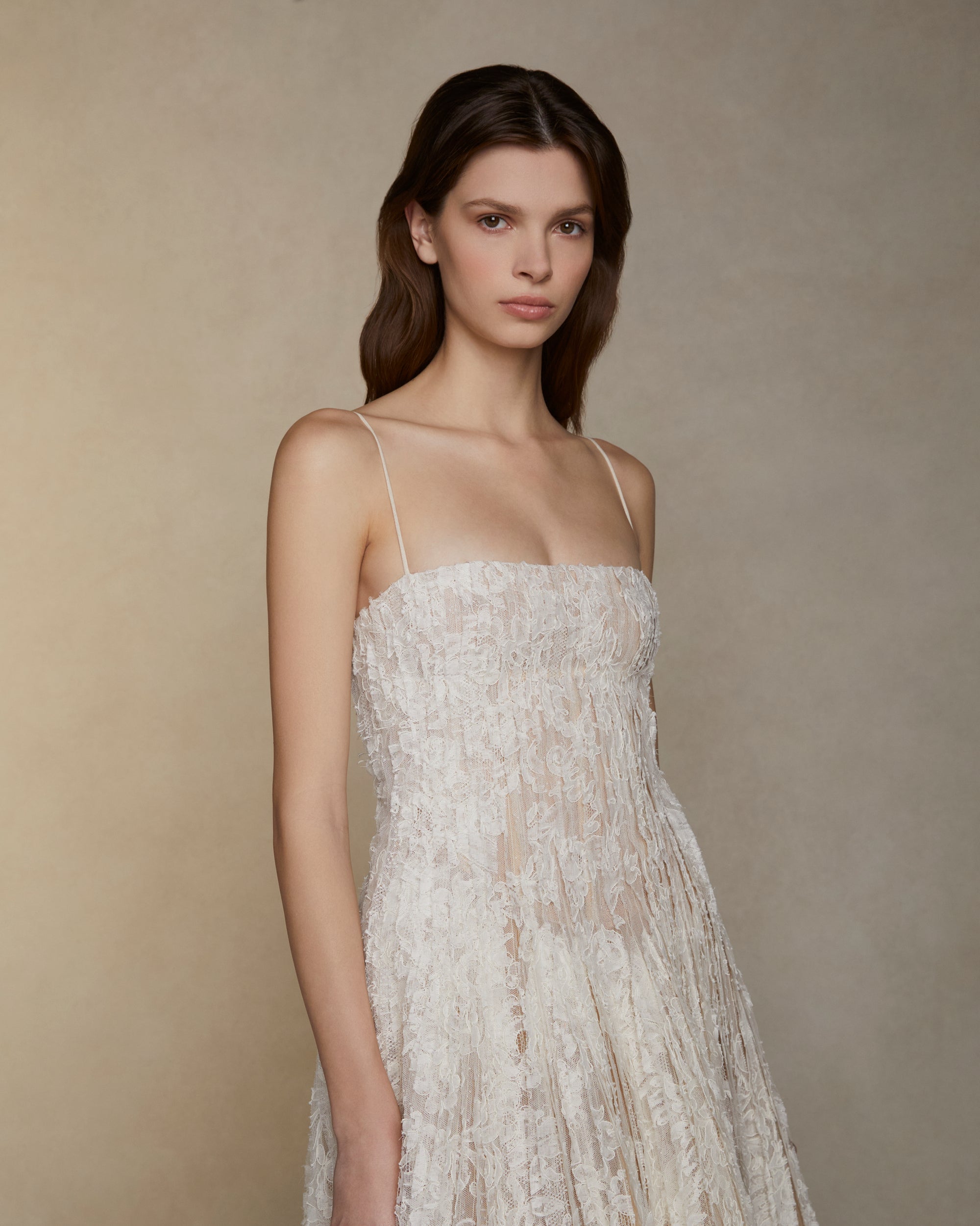 Soft scoop neck ballgown decorated with hand cut Lyon lace strip fabric technique. Layers of Lyon lace strips cascade organically into a released bubble hem train. Internal bustier and invisible zip closure at center back.