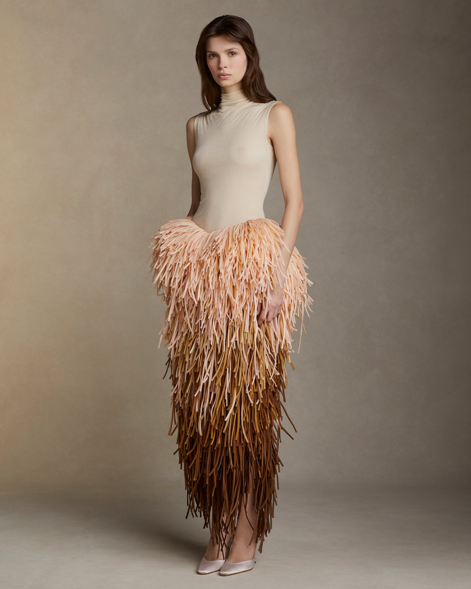 Pegged skirt with layers of silk organza tubular strands dripping down the silhouette in an ombre of pinks, peaches, and soft browns. Side zip closure. 