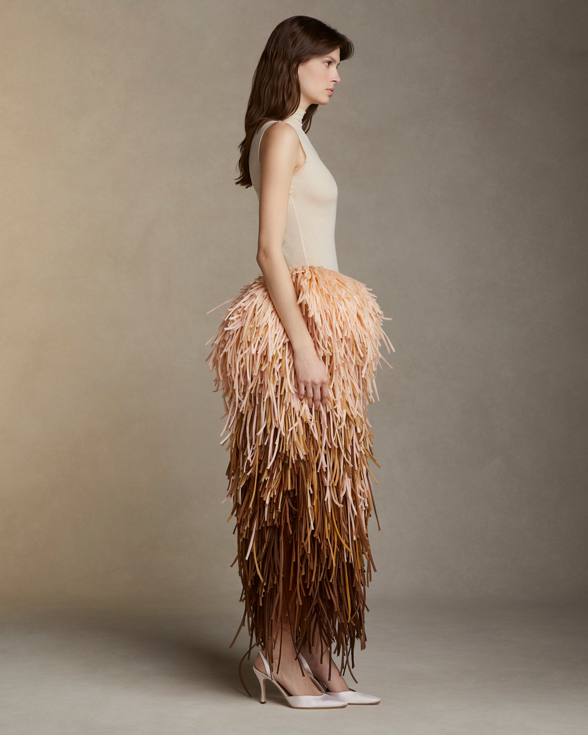 Pegged skirt with layers of silk organza tubular strands dripping down the silhouette in an ombre of pinks, peaches, and soft browns. Side zip closure. 