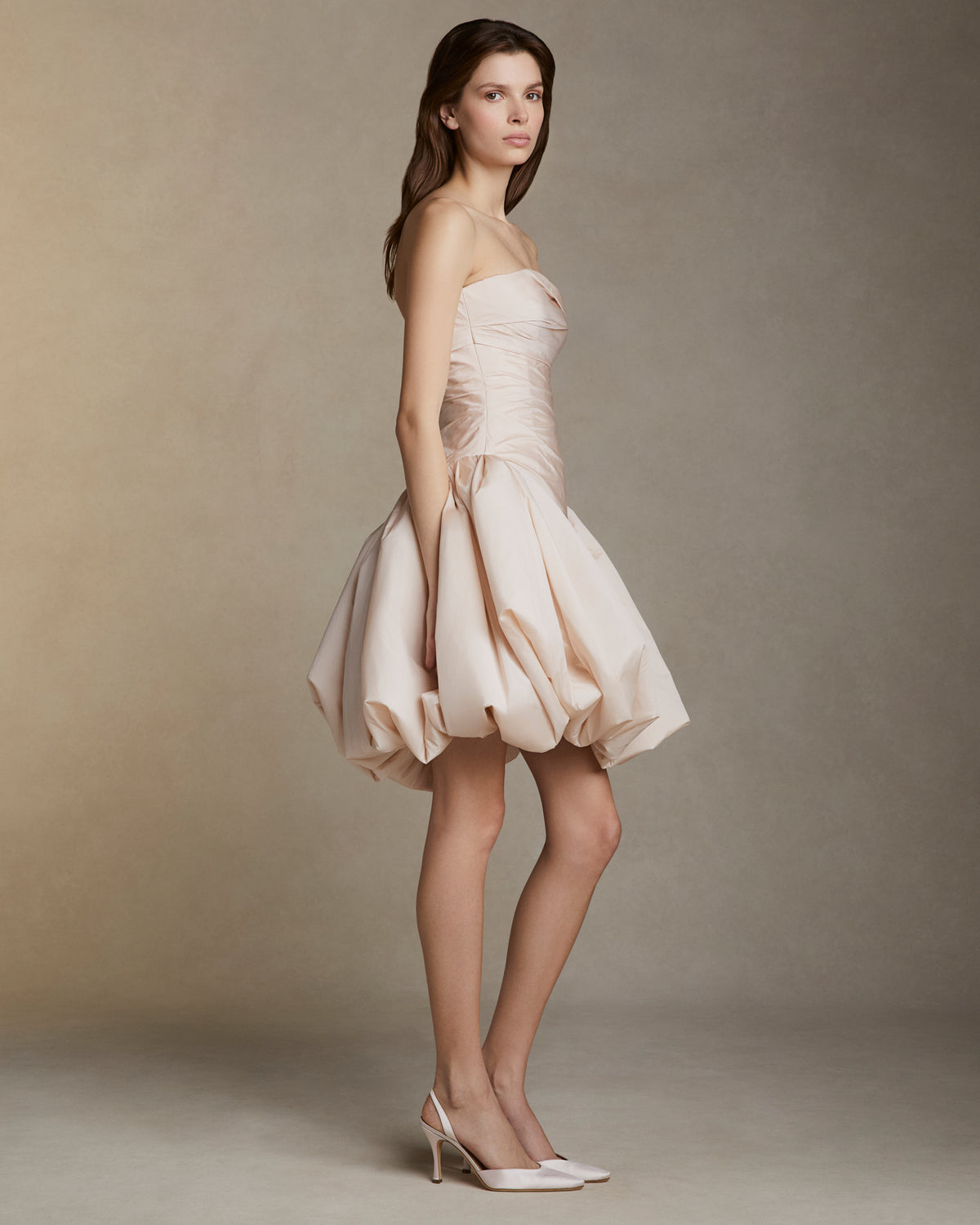 Featherweight silk taffeta draped strapless mini dress with elongated v waistline. Bubble hem skirt releases from the high hip and peels away from the center front. Invisible zip closure at center back.