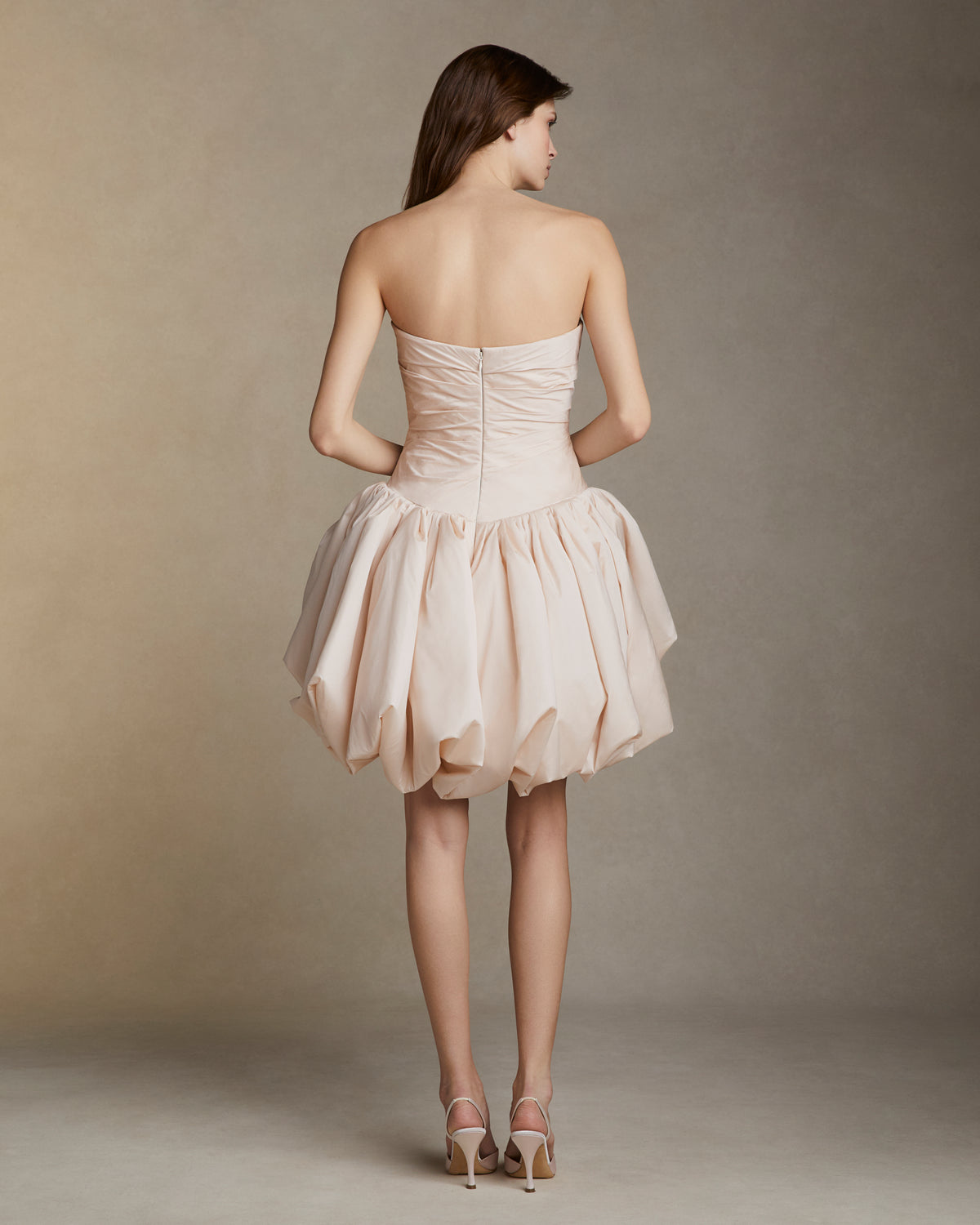 Featherweight silk taffeta draped strapless mini dress with elongated v waistline. Bubble hem skirt releases from the high hip and peels away from the center front. Invisible zip closure at center back.