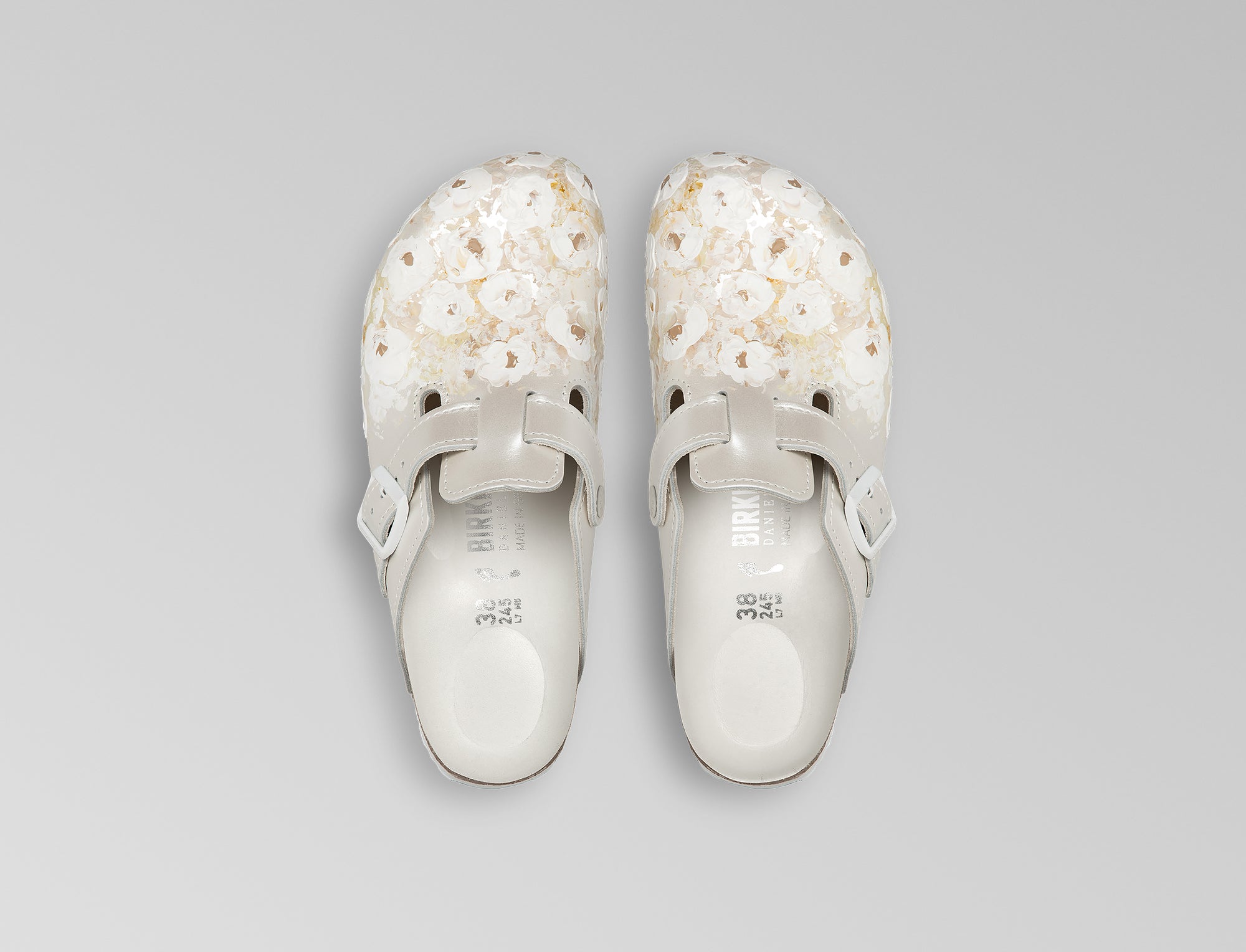 The iconic Boston is updated in an ivory pearlized finish leather with powder coated ivory buckle. Bespoke hand painted florals decorate the leather upper. Hand crafted in Germany and hand painted in France. Exclusively available through Danielle Frankel Studio.- Upper: Delicate satin upper, piped trim edge detail for premium tuxedo like finish- Footbed: Anatomical shaped BIRKENSTOCK cork latex Footbed lined with premium Nappa Leather- Sole: EVA die cut outsole with a custom design, blending classic BIRKENSTOCK bone pattern with delicate leaf inspired detailing 