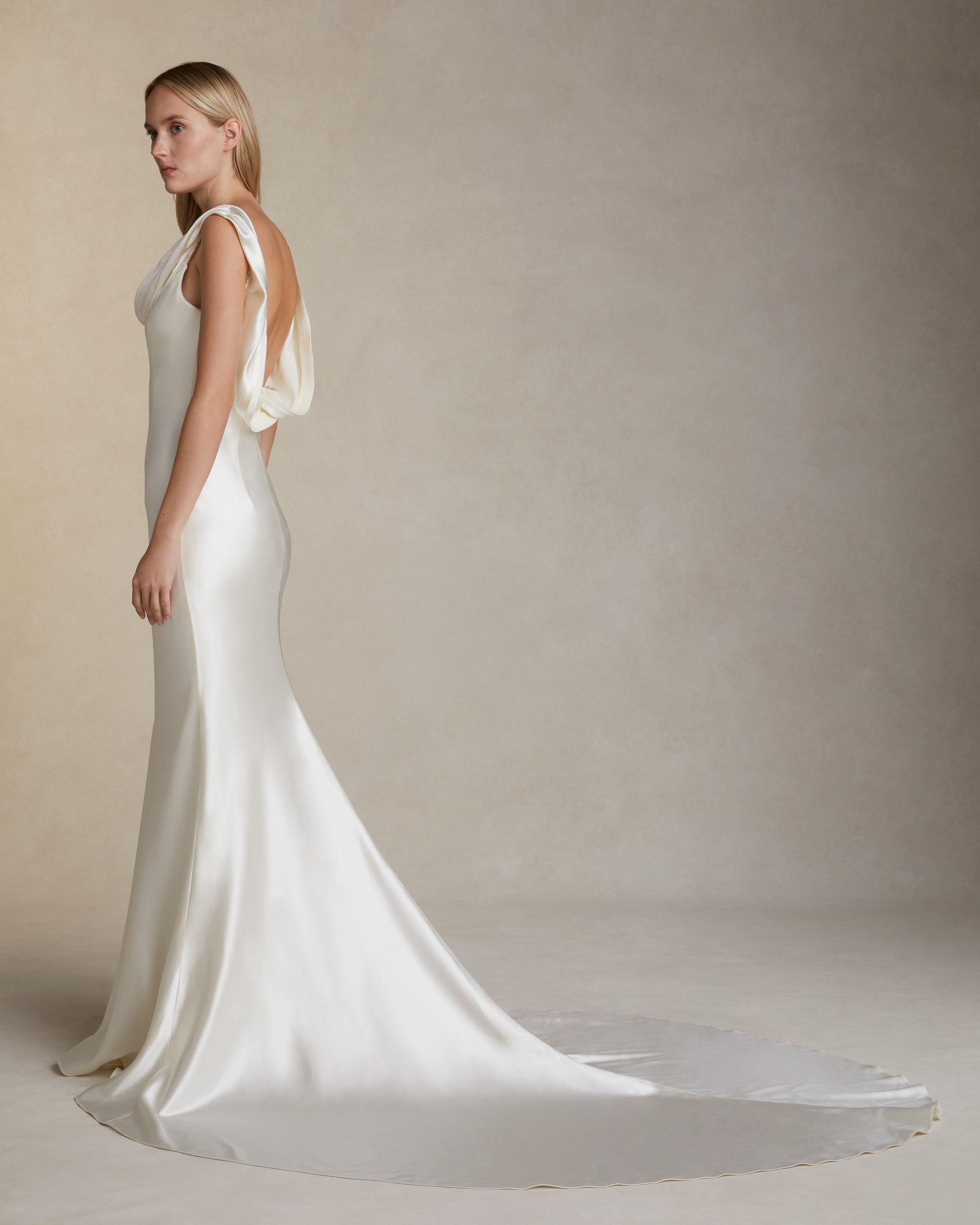 Bias cut silk wool gown with layered ribbon trim detail peeling away from neckline and trailing down back. Invisible zip closure at center back.