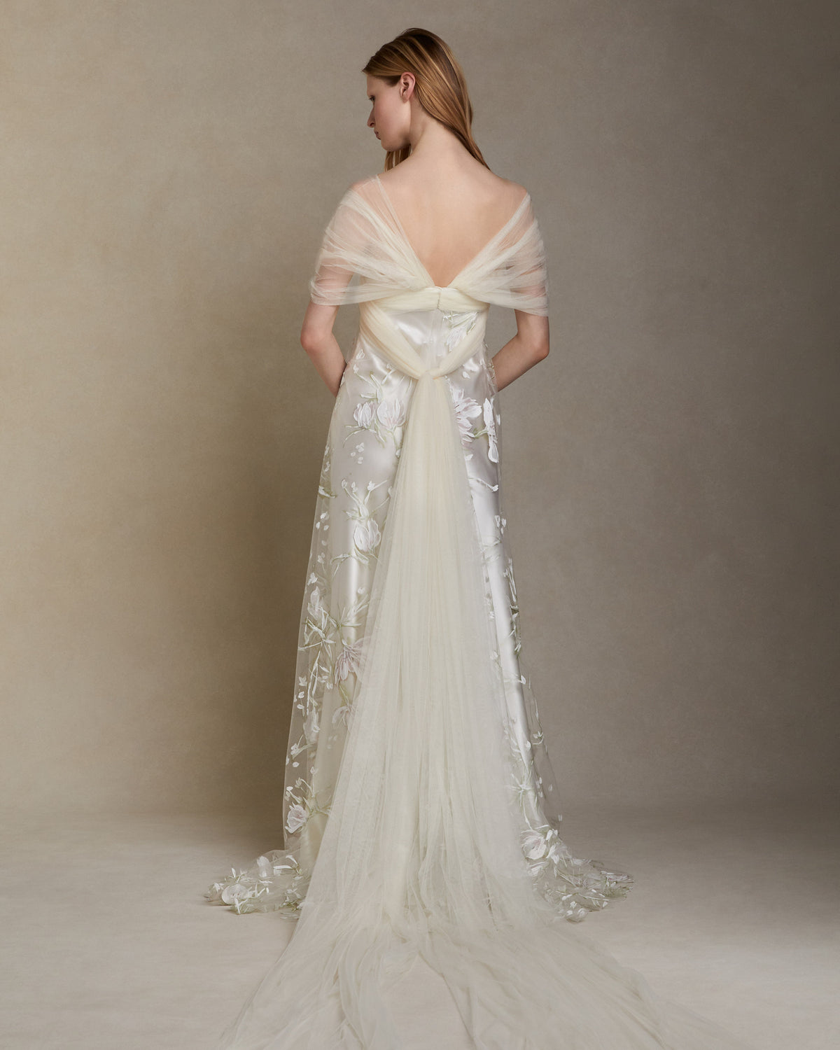 Silk wool gown with hand painted floral illusion tulle overlay. Draped soft tulle bodice with swagged sleeves. Invisible zip closure at center back.