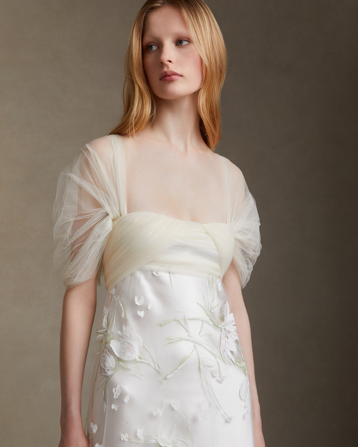Silk wool gown with hand painted floral illusion tulle overlay. Draped soft tulle bodice with swagged sleeves. Invisible zip closure at center back.