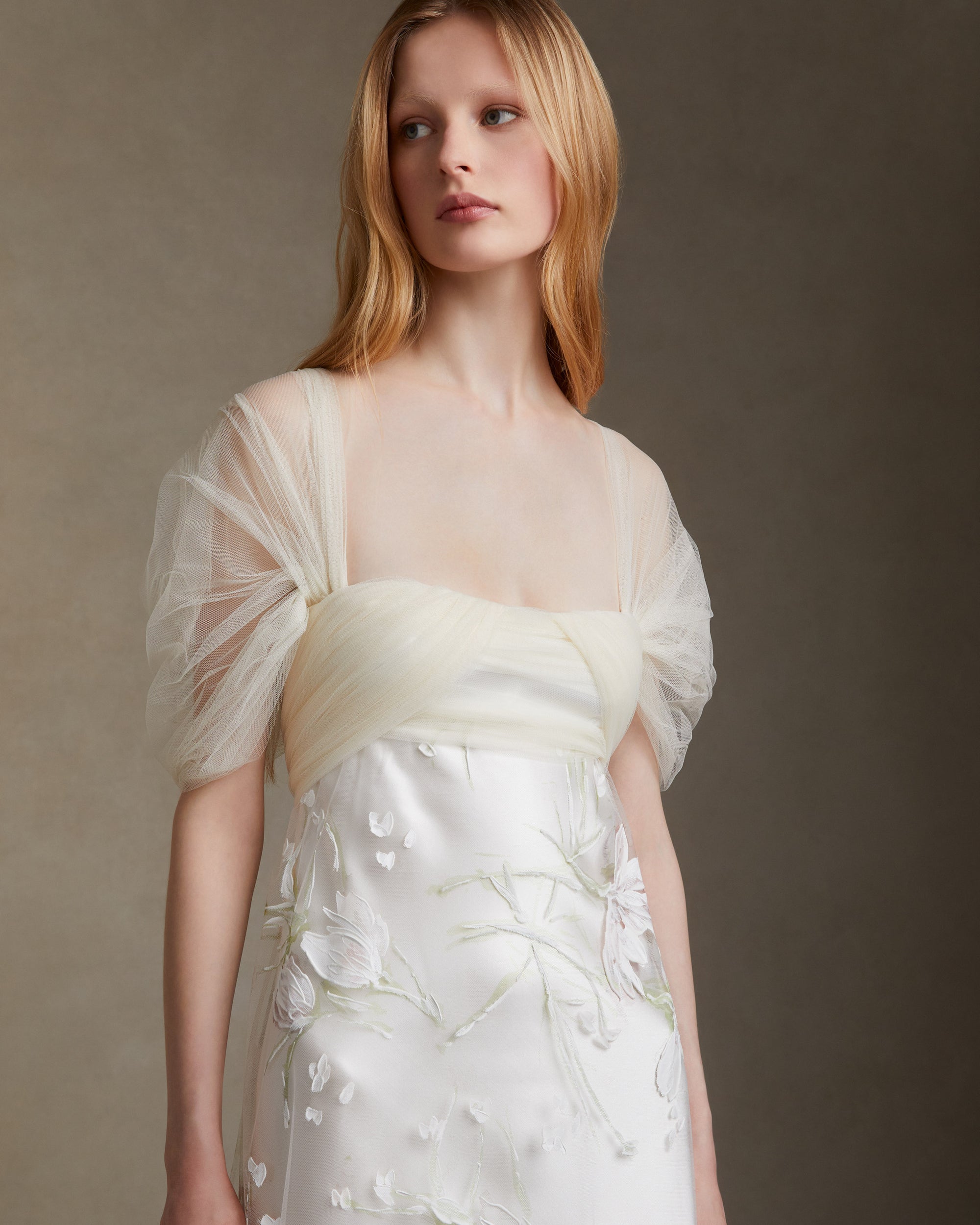Silk wool gown with hand painted floral illusion tulle overlay. Draped soft tulle bodice with swagged sleeves. Invisible zip closure at center back.
