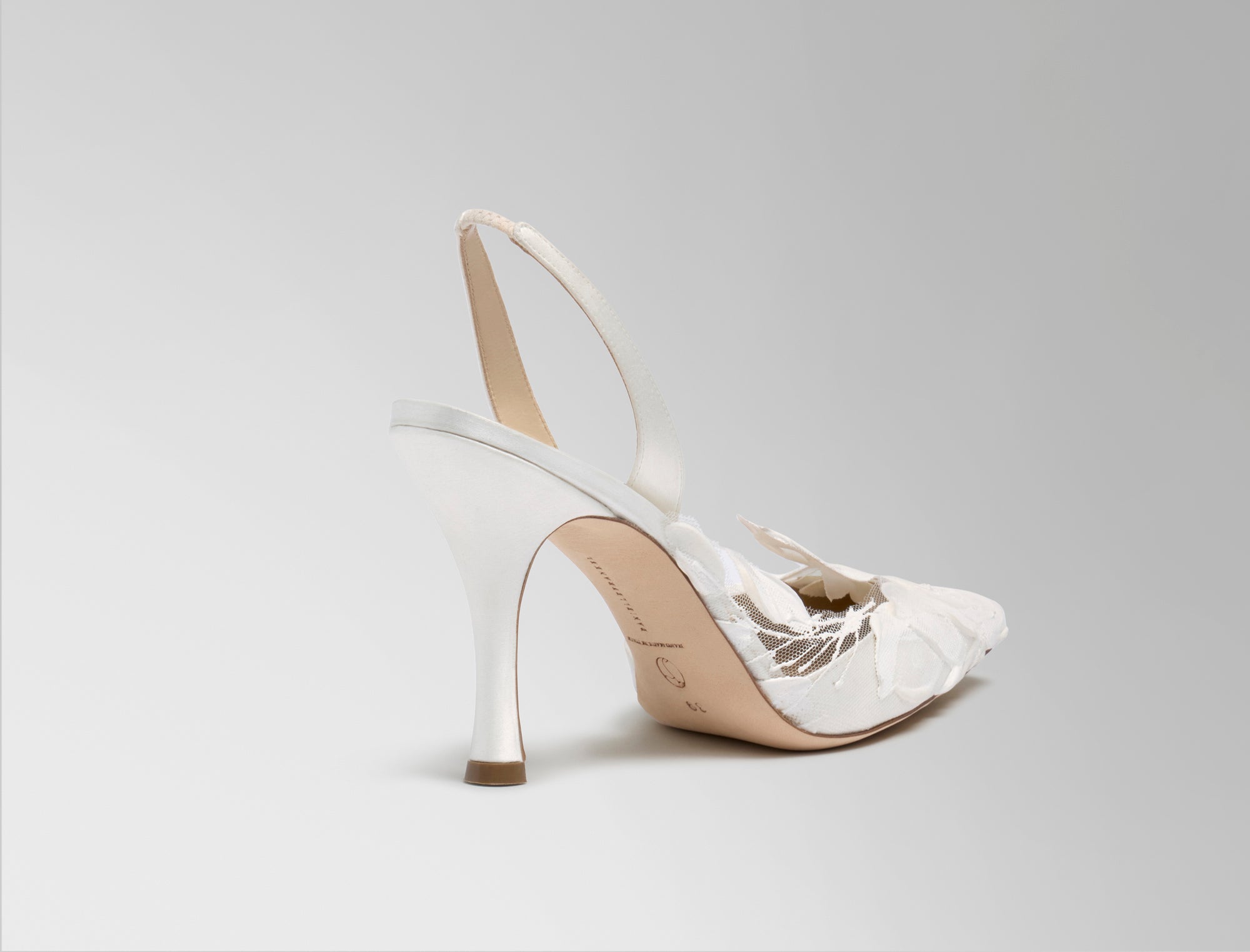Classic slingback crafted in Italy of ivory satin with hand painted ivory floral detail. Elongated round toe and 90mm heel.