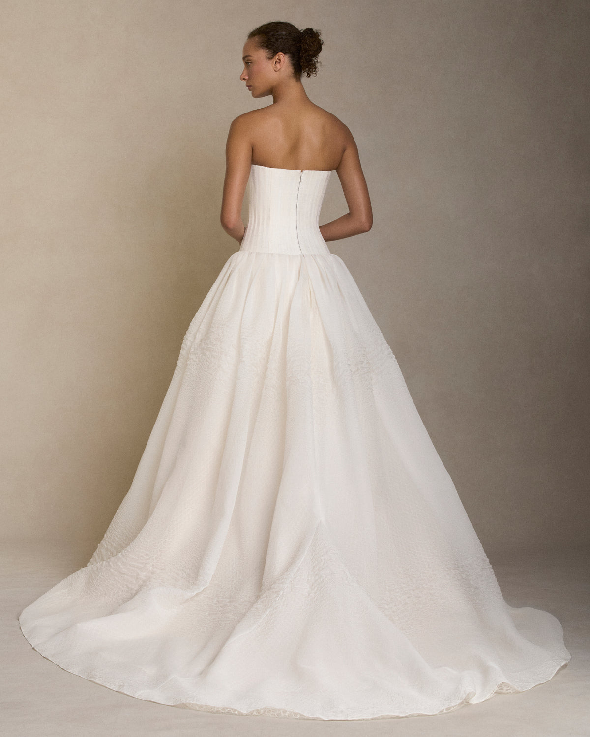 Strapless drop waist silk linen organza ballgown with grosgrain boning detail shaping the bustier. Layered textured cloqué organza drop waist ball skirt with honeycomb lace underlay. Boned internal bustier, internal grosgrain belt and invisible zip closure at center back