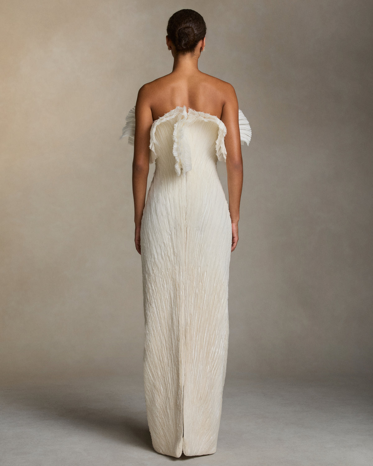 Sculptural column gown with exaggerated flared neckline. Layered fans of stripped crinkle organza embroidery radiate from the waist. Boned internal double zip bustier with internal grosgrain belt. 