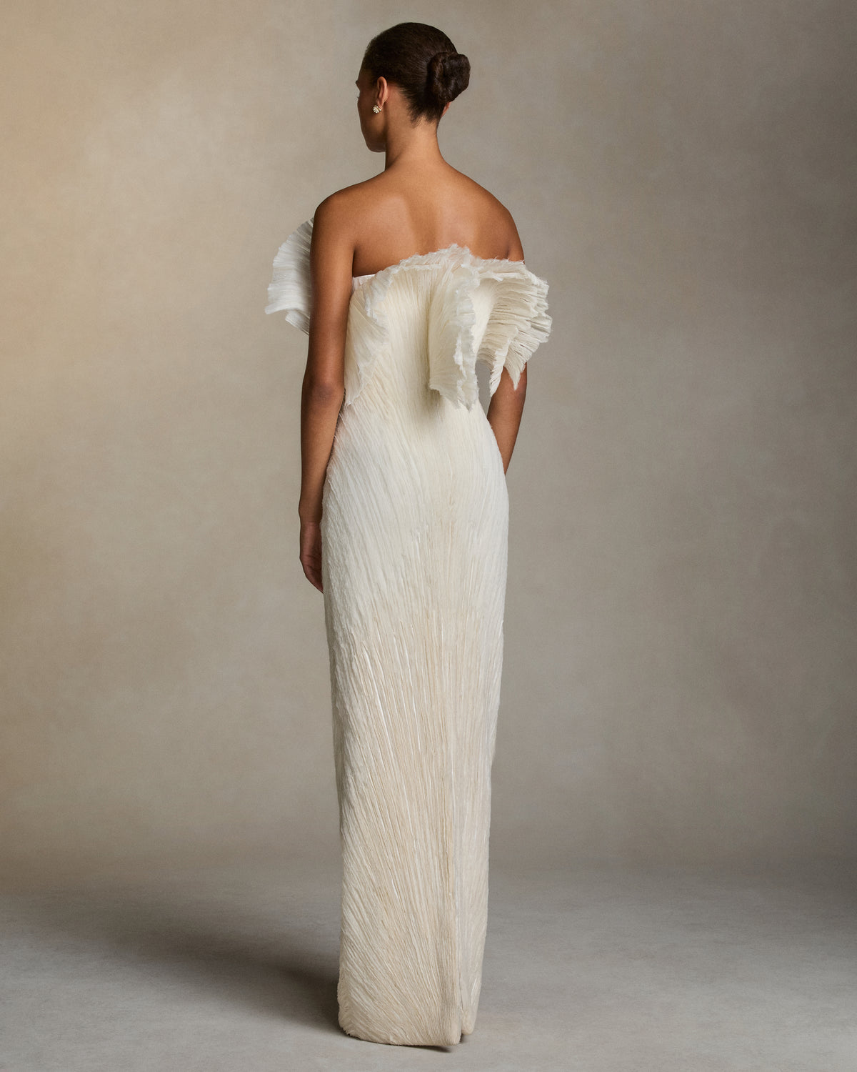 Sculptural column gown with exaggerated flared neckline. Layered fans of stripped crinkle organza embroidery radiate from the waist. Boned internal double zip bustier with internal grosgrain belt. 