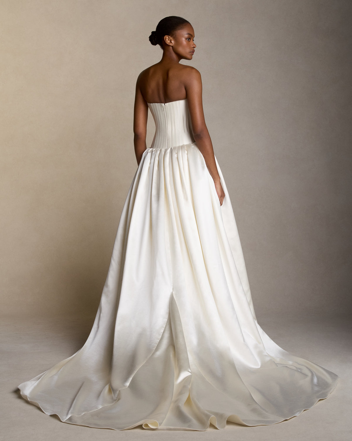 Silk wool strapless drop waist ballgown with trapunto-stitched boning shaping the bustier. Silk wool twill bodice releases into a silk wool satin gathered ball skirt. Boned internal bustier, internal grosgrain belt and invisible zip closure at center back.