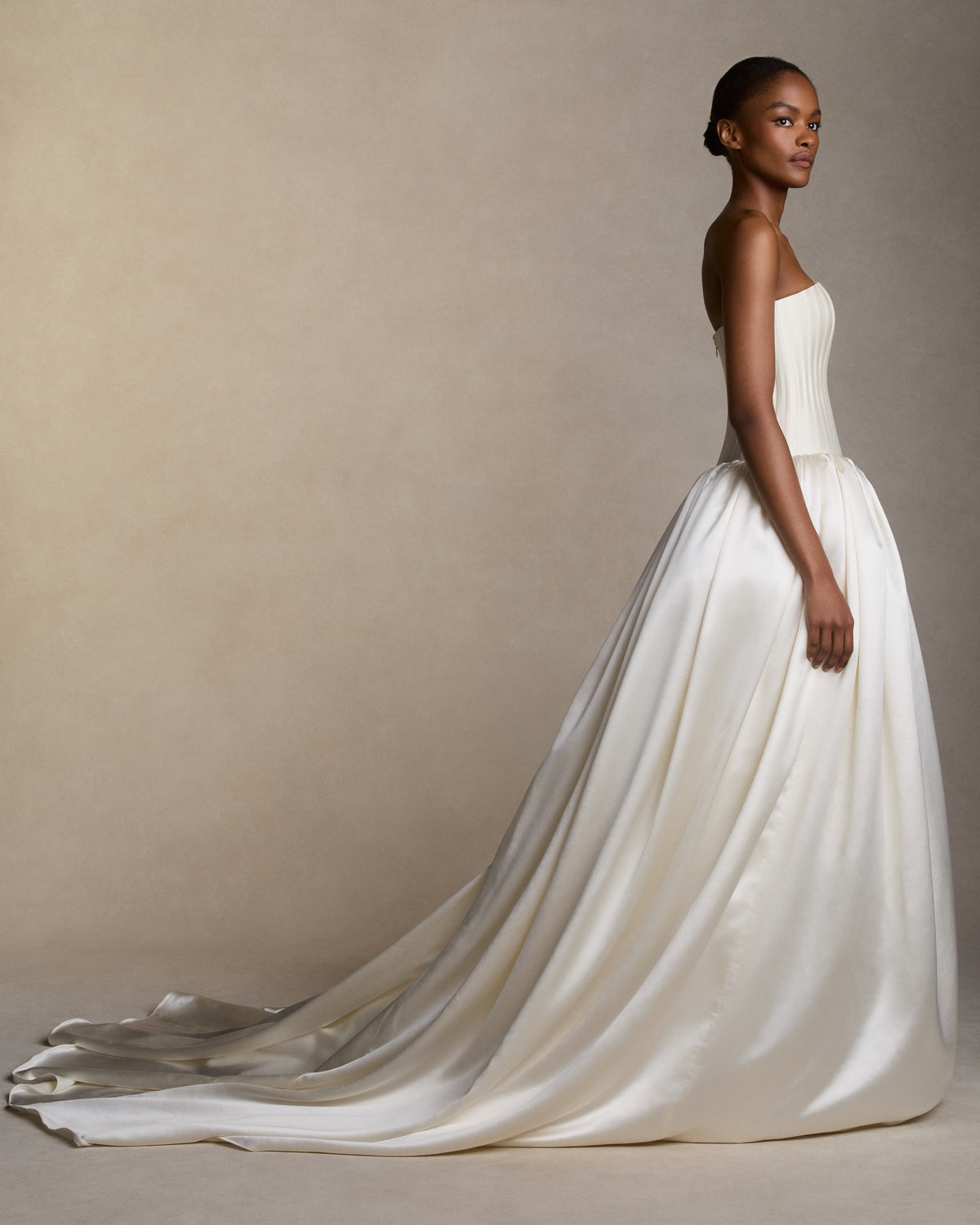 Silk wool strapless drop waist ballgown with trapunto-stitched boning shaping the bustier. Silk wool twill bodice releases into a silk wool satin gathered ball skirt. Boned internal bustier, internal grosgrain belt and invisible zip closure at center back.